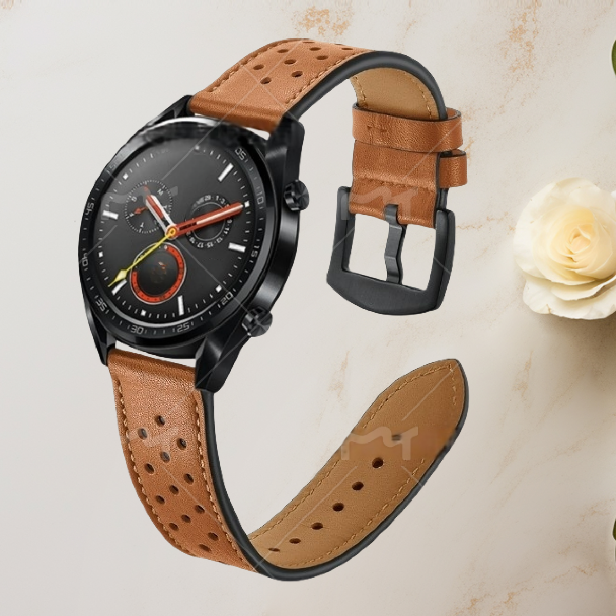 Un orologio nero con cinturino in pelle marrone. L'orologio è su una superficie marrone chiaro vicino a un fiore.