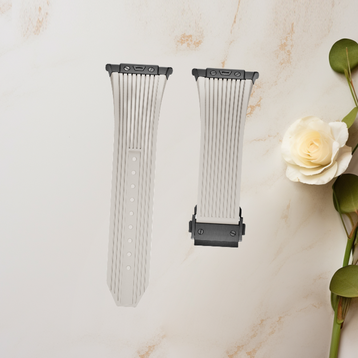 Due cinturini bianchi per orologi con un design floreale e una rosa bianca su una superficie di marmo.