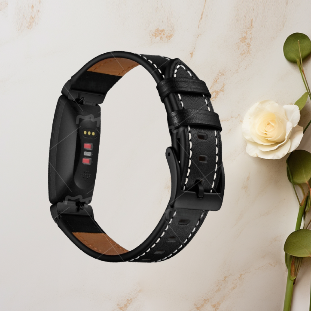Eine schwarze Smartwatch mit einem schwarz-weißen Lederarmband, platziert in der Nähe einer weißen Blume, auf einer beigen Oberfläche.