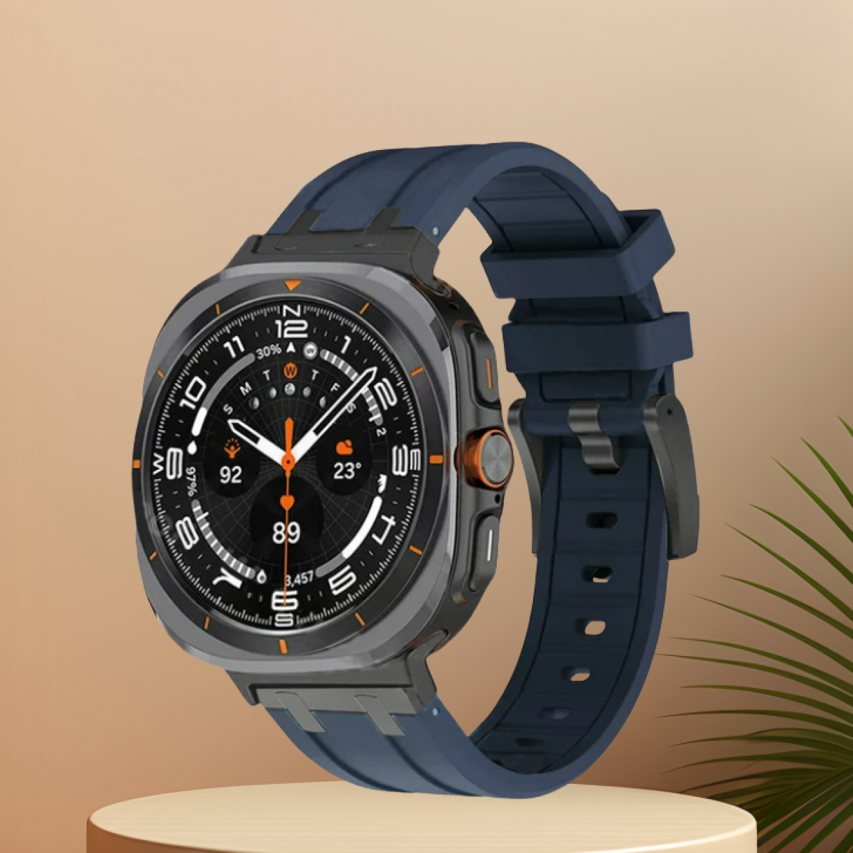 Uno smartwatch argentato con cinturino blu su un piedistallo. Mostra l'ora.