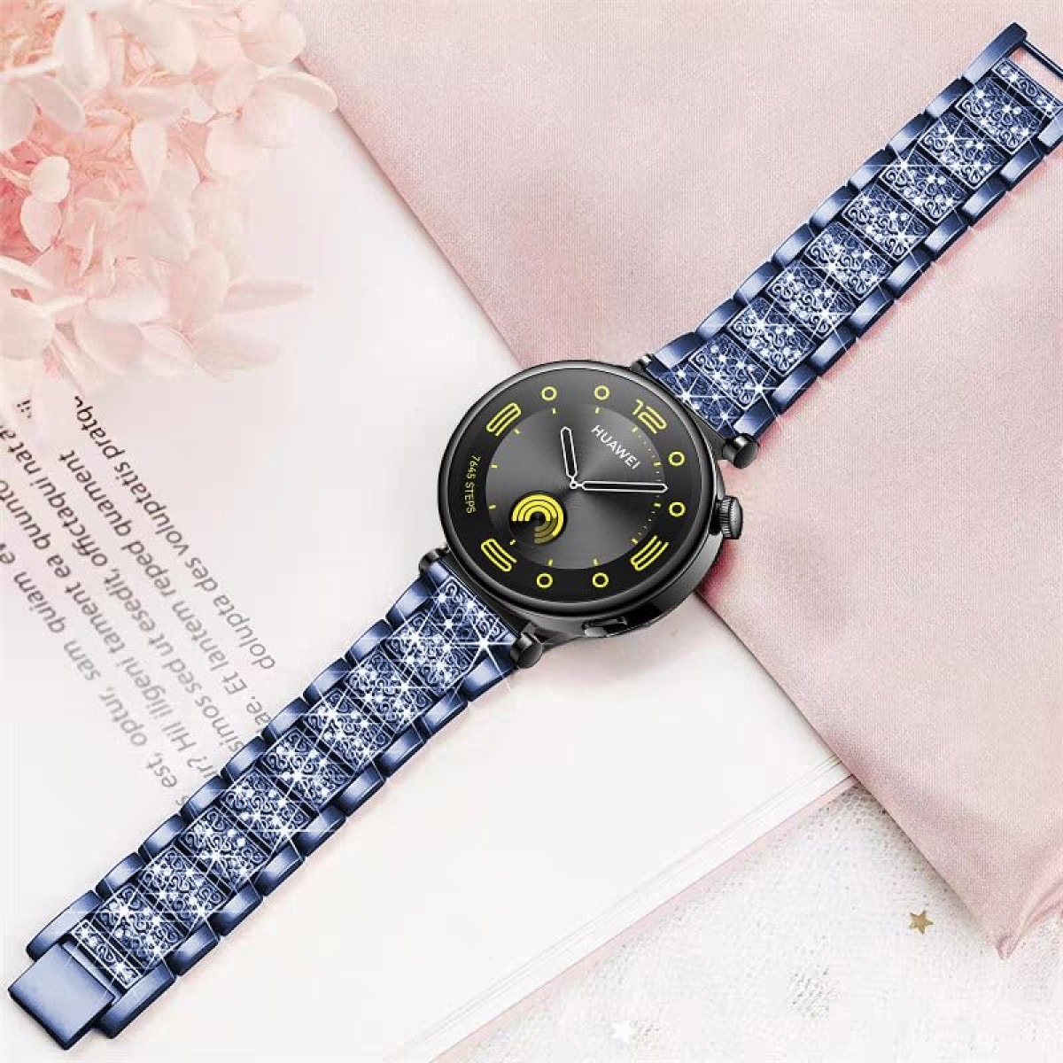 Smartwatch mit blauem, geschmücktem Armband. Das Zifferblatt ist dunkel mit gelben und weißen Details.