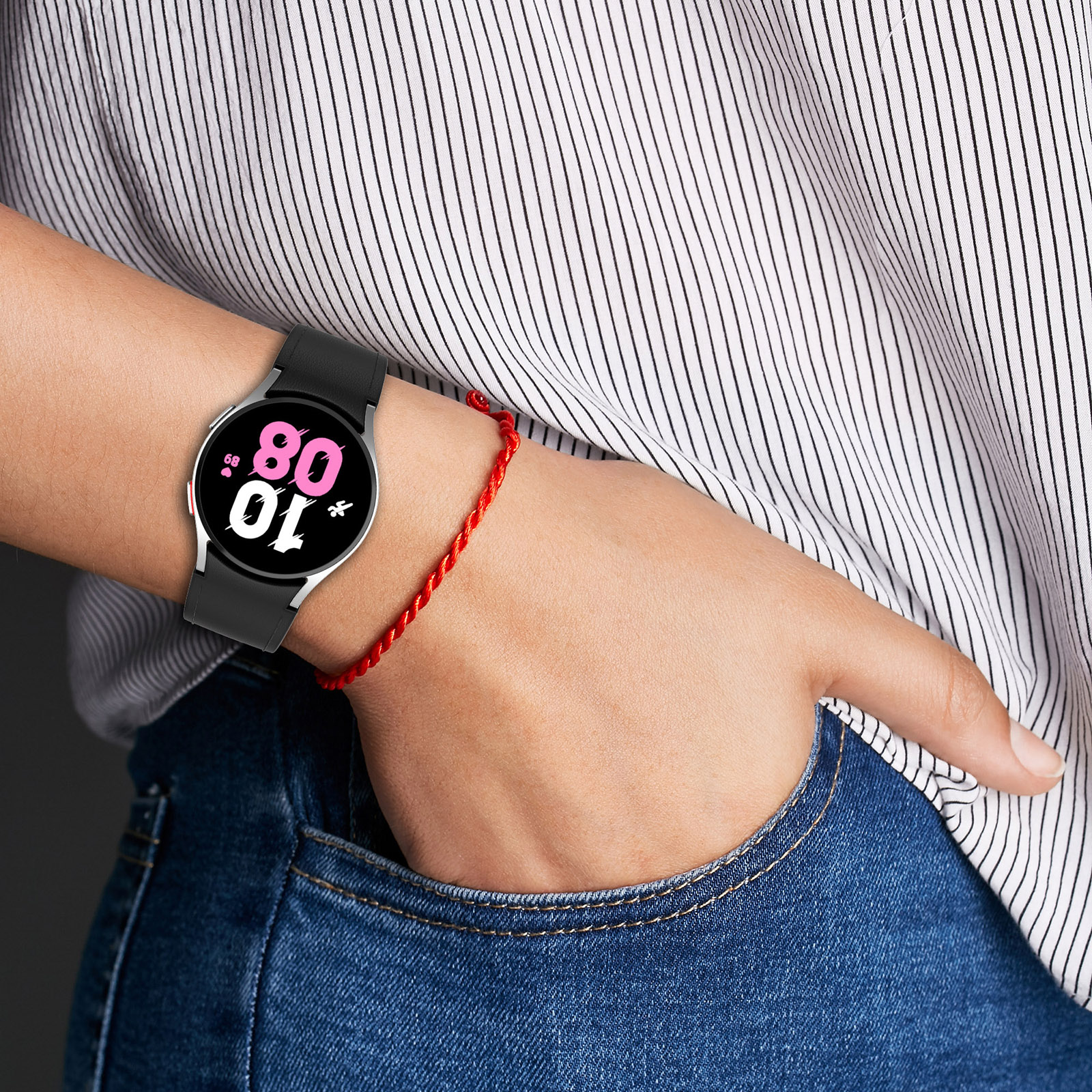 Handgelenk mit schwarzer Smartwatch und rotem Armband.