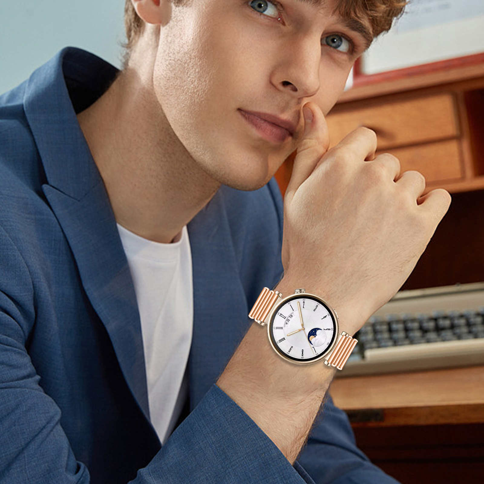 Un uomo che indossa un orologio, lo sta guardando. Indossa una giacca. L'orologio ha un cinturino dorato e un quadrante bianco.