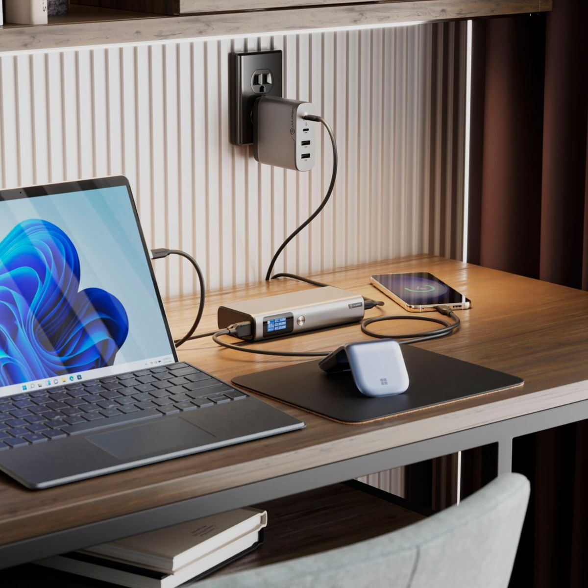 Un'impostazione da scrivania con laptop, caricabatterie, telefono e mouse.