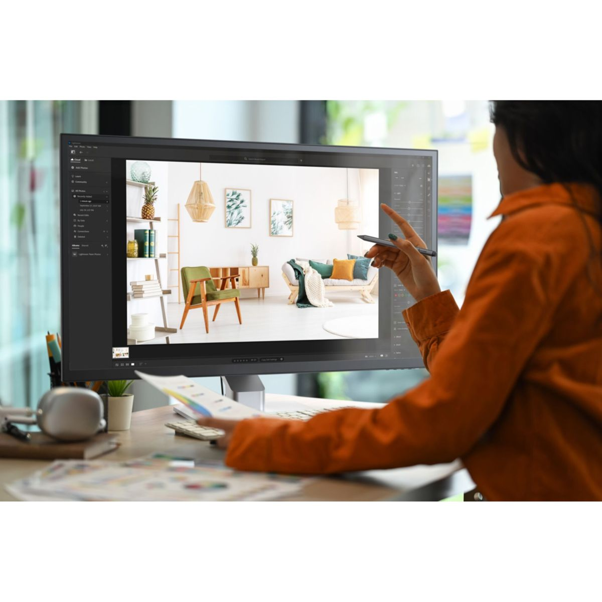 Kobieta wskazuje na monitor z salonem. Biurko z papierami na pierwszym planie.