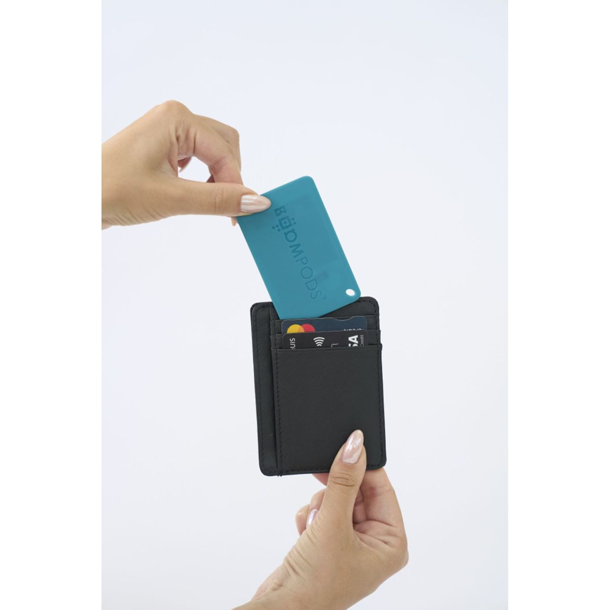 Ręce trzymające czarny portfel, wyjmujące z niego turkusową kartę. Widoczne są inne karty.