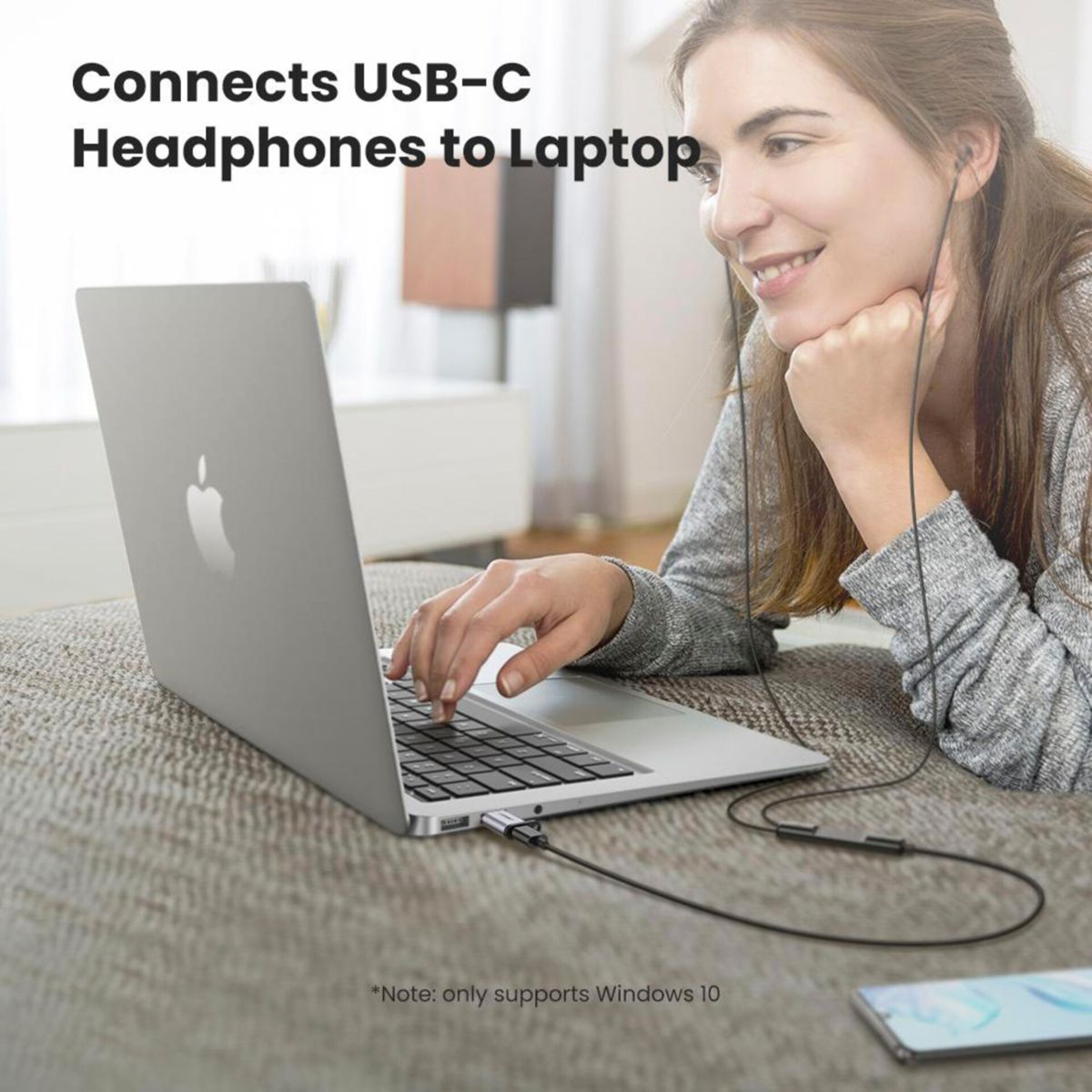 Mujer escuchando música en portátil conectado a auriculares USB-C mediante adaptador UGREEN.