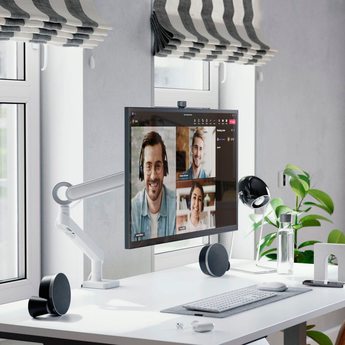 Ein Desktop-Setup mit einem Monitor, der einen Videoanruf zeigt. Der Schreibtisch hat Lautsprecher.