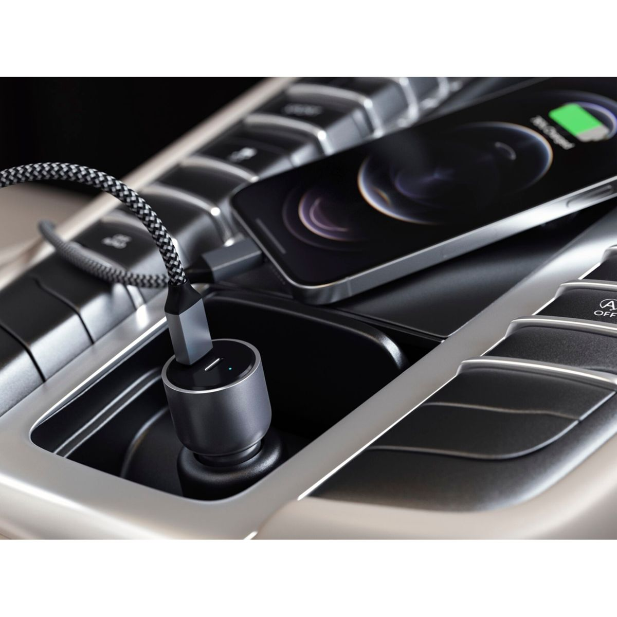 Un telefono si carica in auto. Un cavo di ricarica si collega a un caricatore nero nella console.