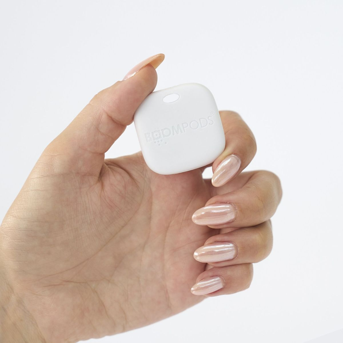 Una mano che tiene un dispositivo quadrato bianco. Il dispositivo ha il testo: BODMPODS.
