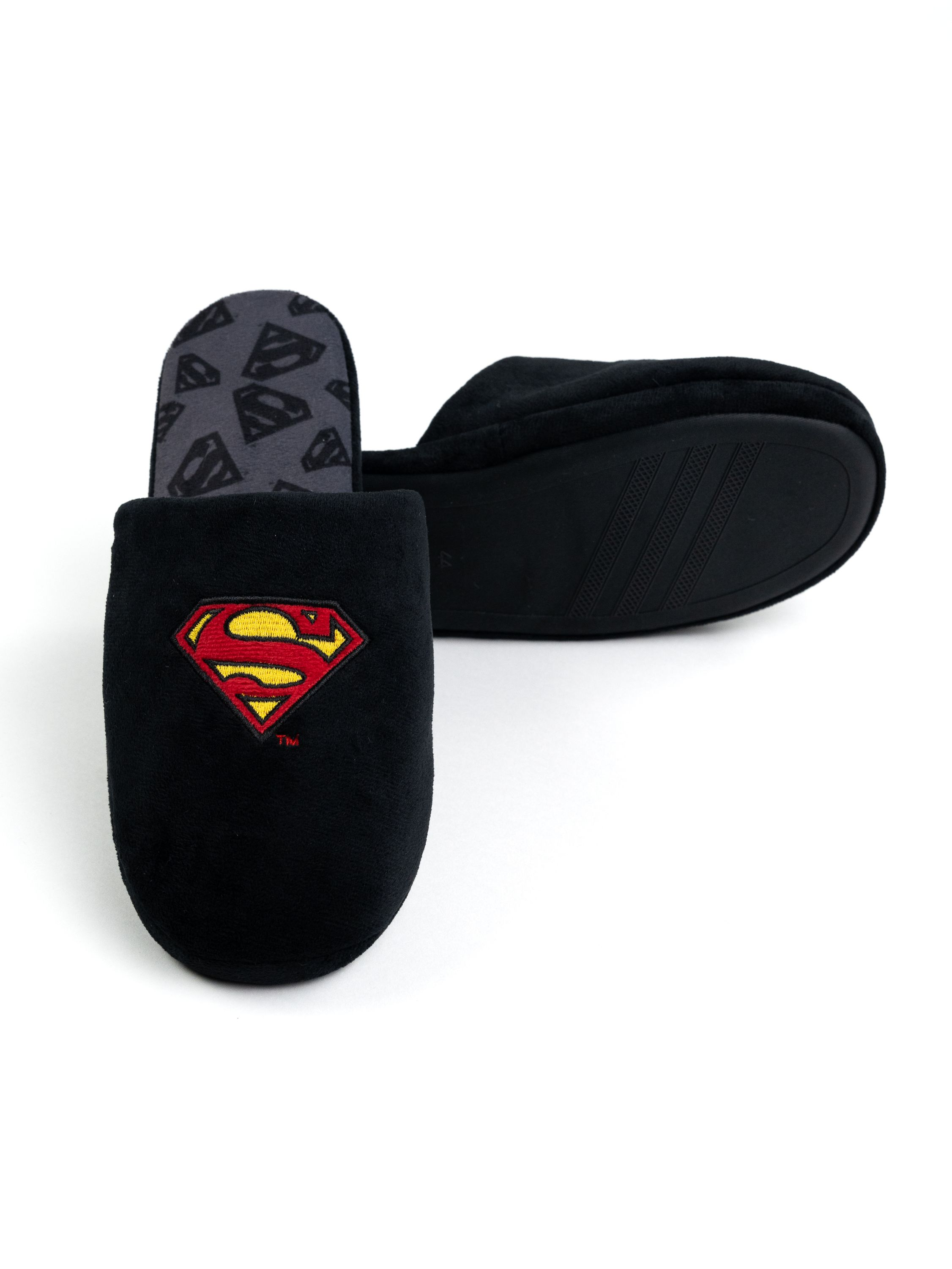 Schwarze Superman-Hausschuhe. Rotes und gelbes Superman-Logo. Grauer Innenraum mit Superman-Logos. Isoliert.