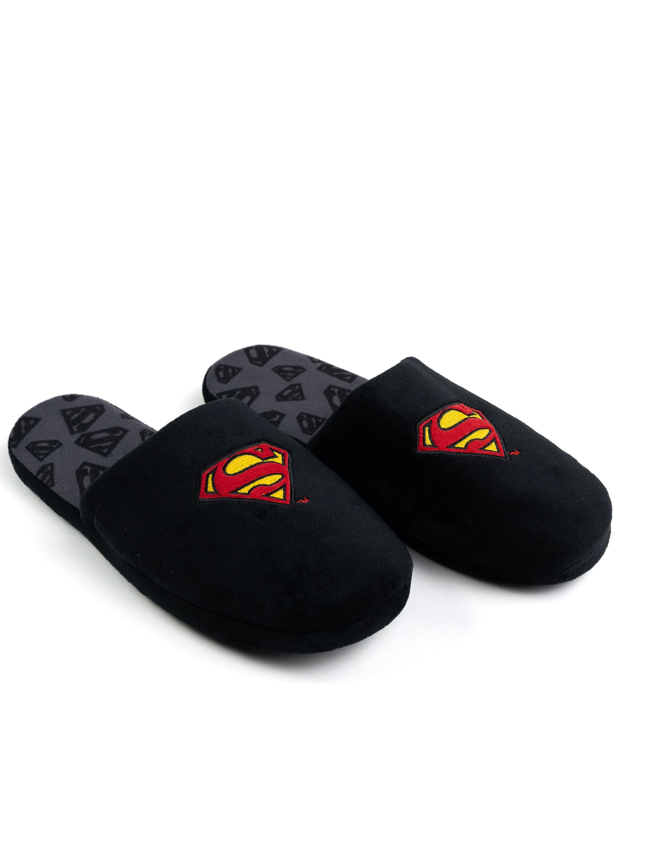 Schwarze Superman-Hausschuhe. Superman-Logo auf jedem Hausschuh. Grauer Innenraum mit Superman-Logos. Isoliert.