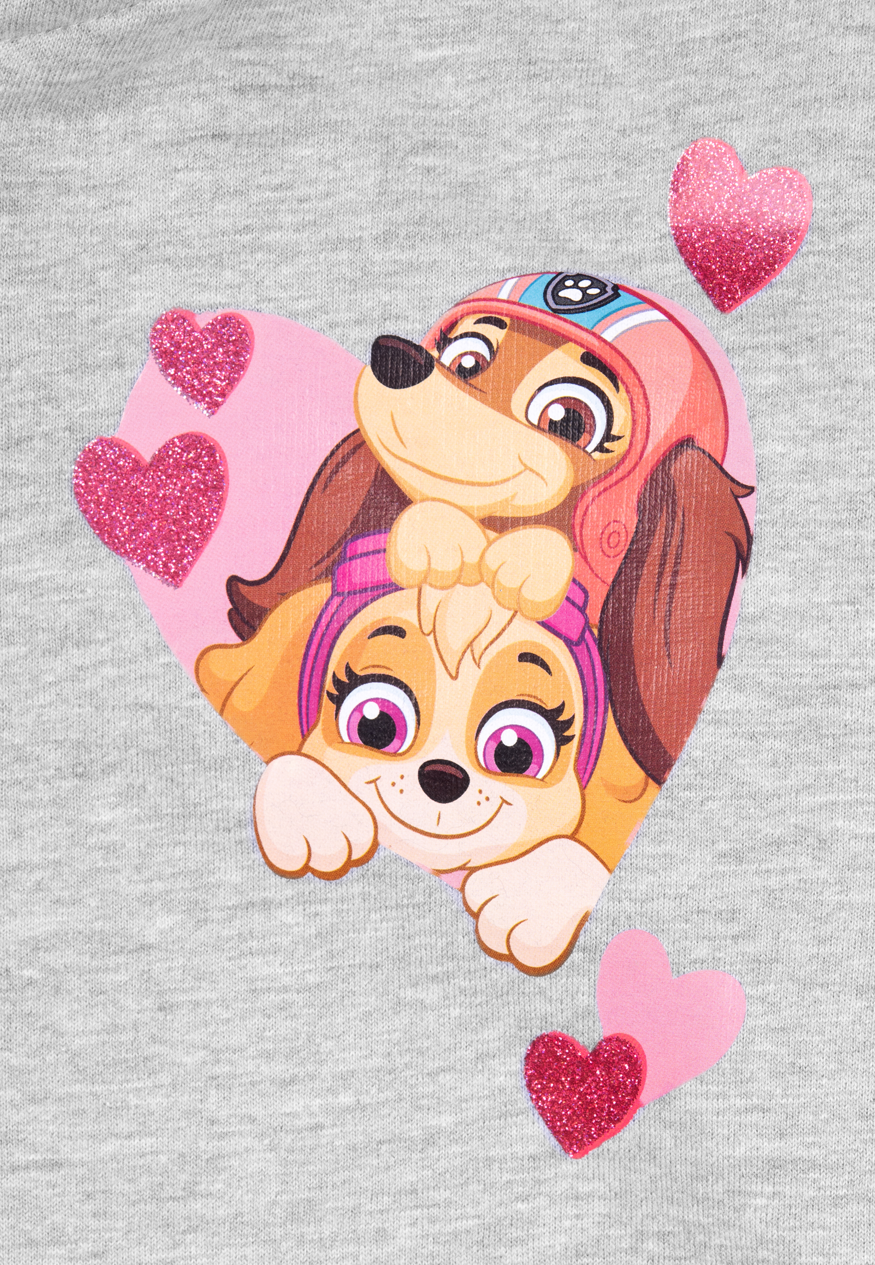 Graues T-Shirt mit Herzdesign mit zwei Paw Patrol-Welpen. Rosa Glitzerherzen umgeben das Bild.