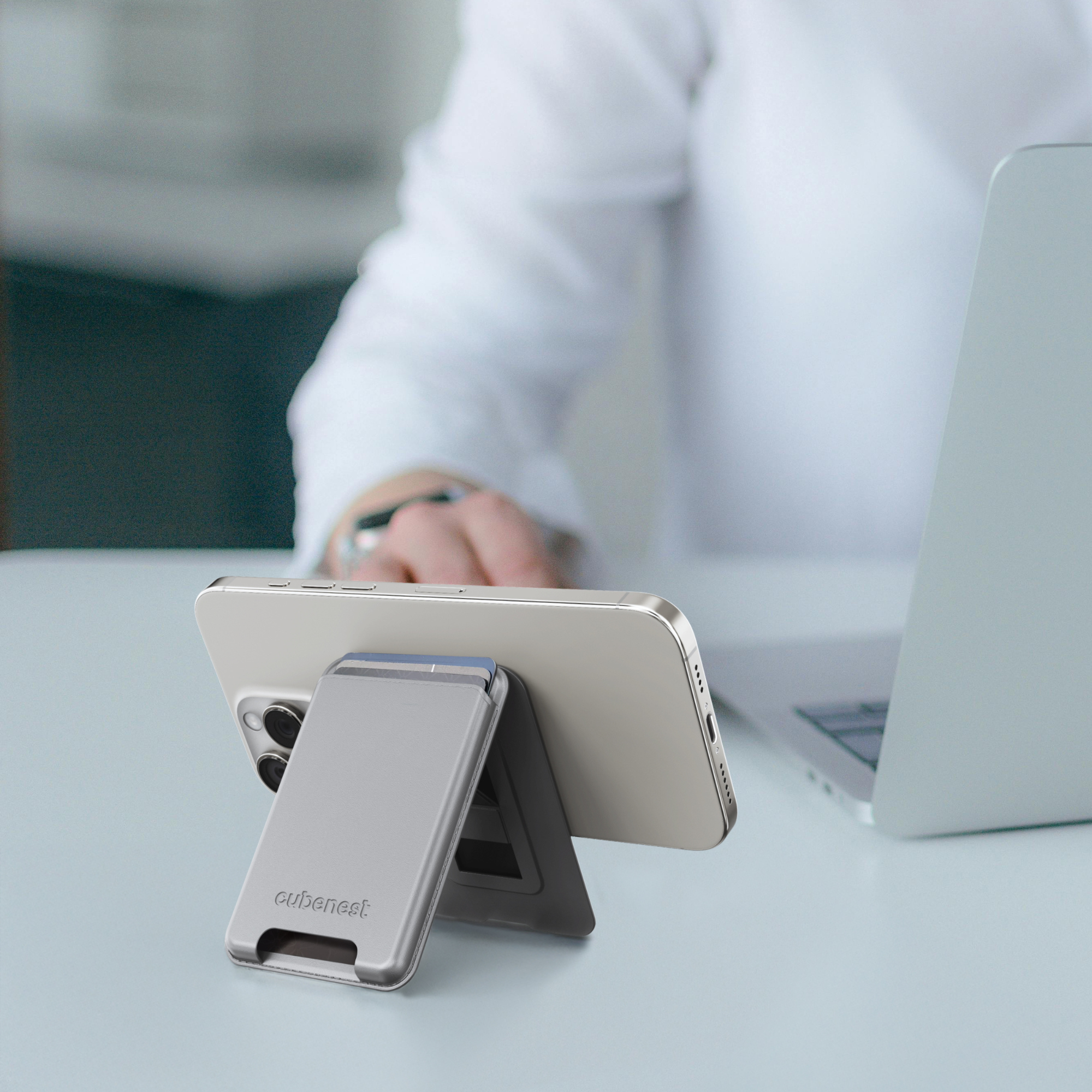 Silberner Telefonständer mit einem Telefon darauf. Das Telefon ist auf einem Schreibtisch abgewinkelt.