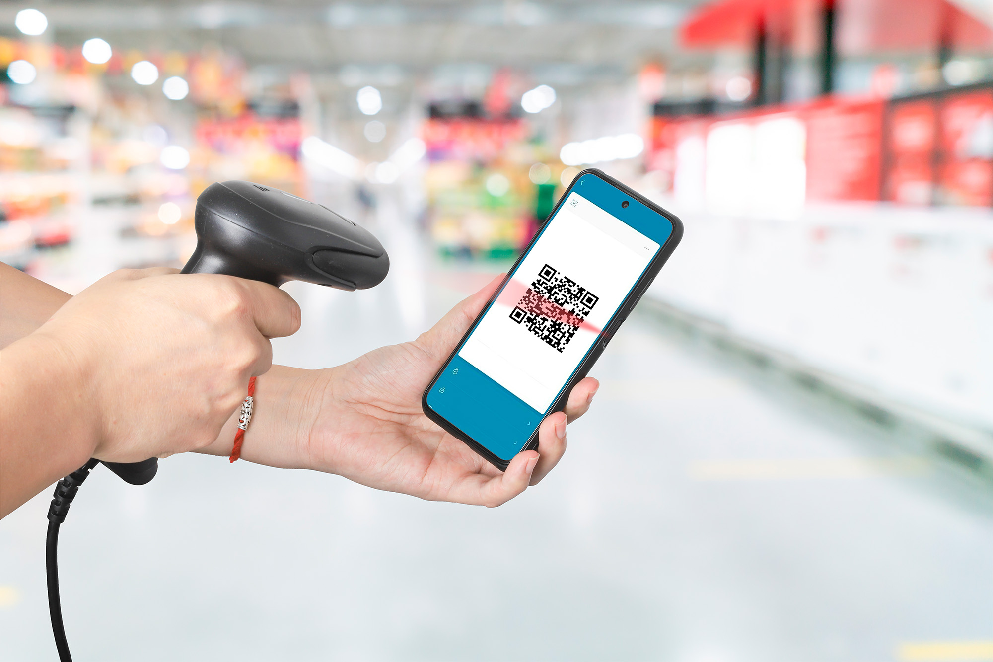 Una persona che scansiona un codice QR su un telefono con uno scanner di codici a barre in un supermercato sfocato.