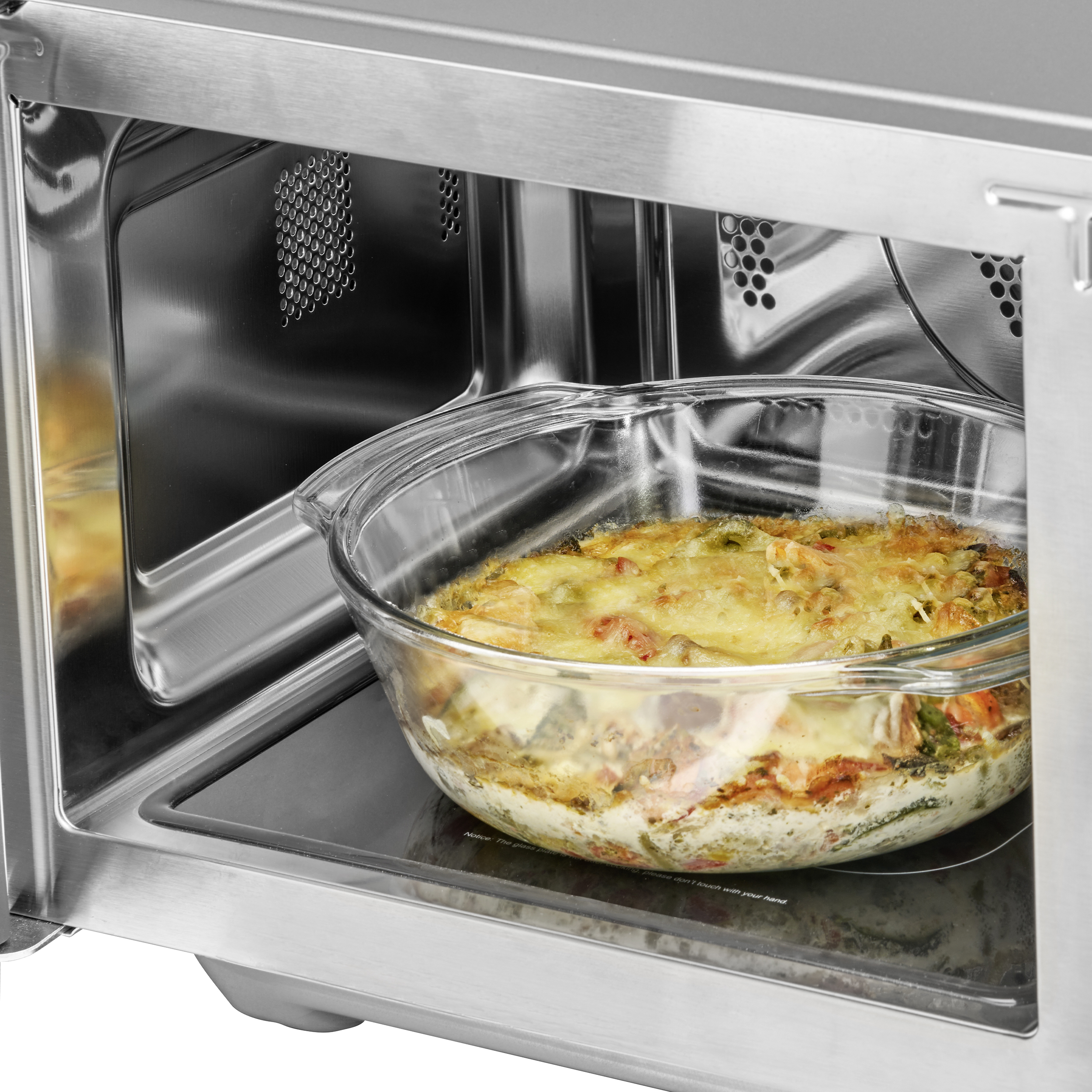 Backofeninnenraum mit Glasgeschirr mit gekochtem Essen. Edelstahlrahmen. Das Gericht befindet sich in der Mitte.