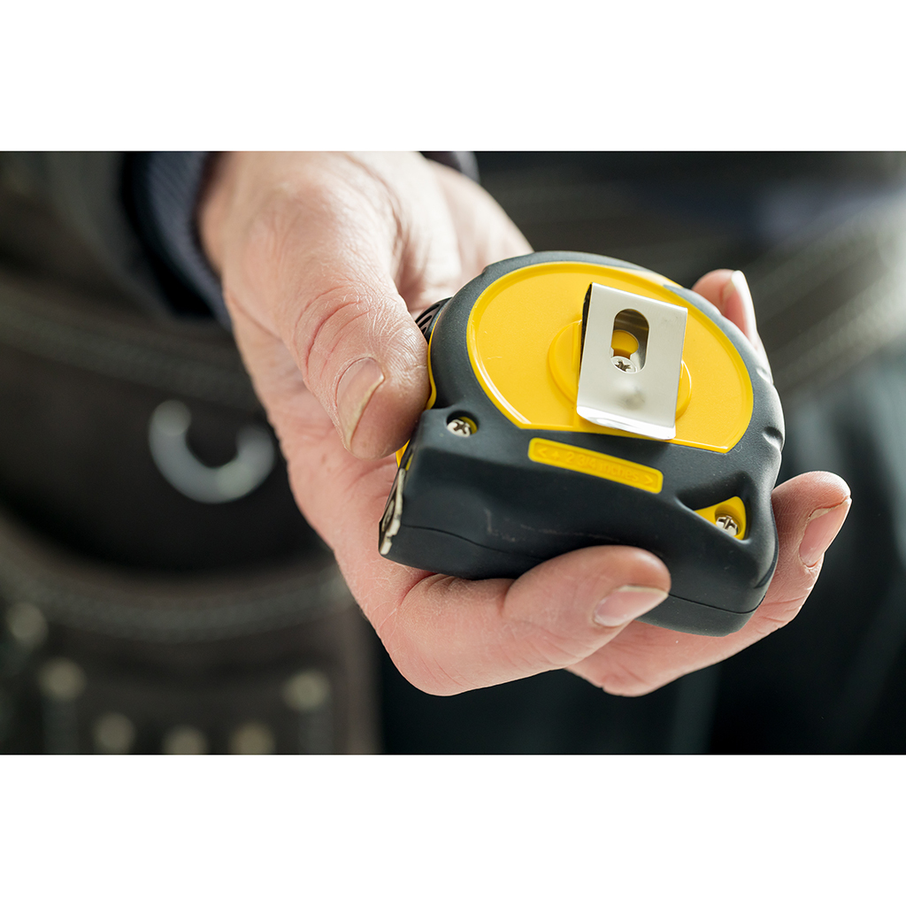 Dłoń trzymająca żółto-czarną miarkę. Miarka jest zamknięta.