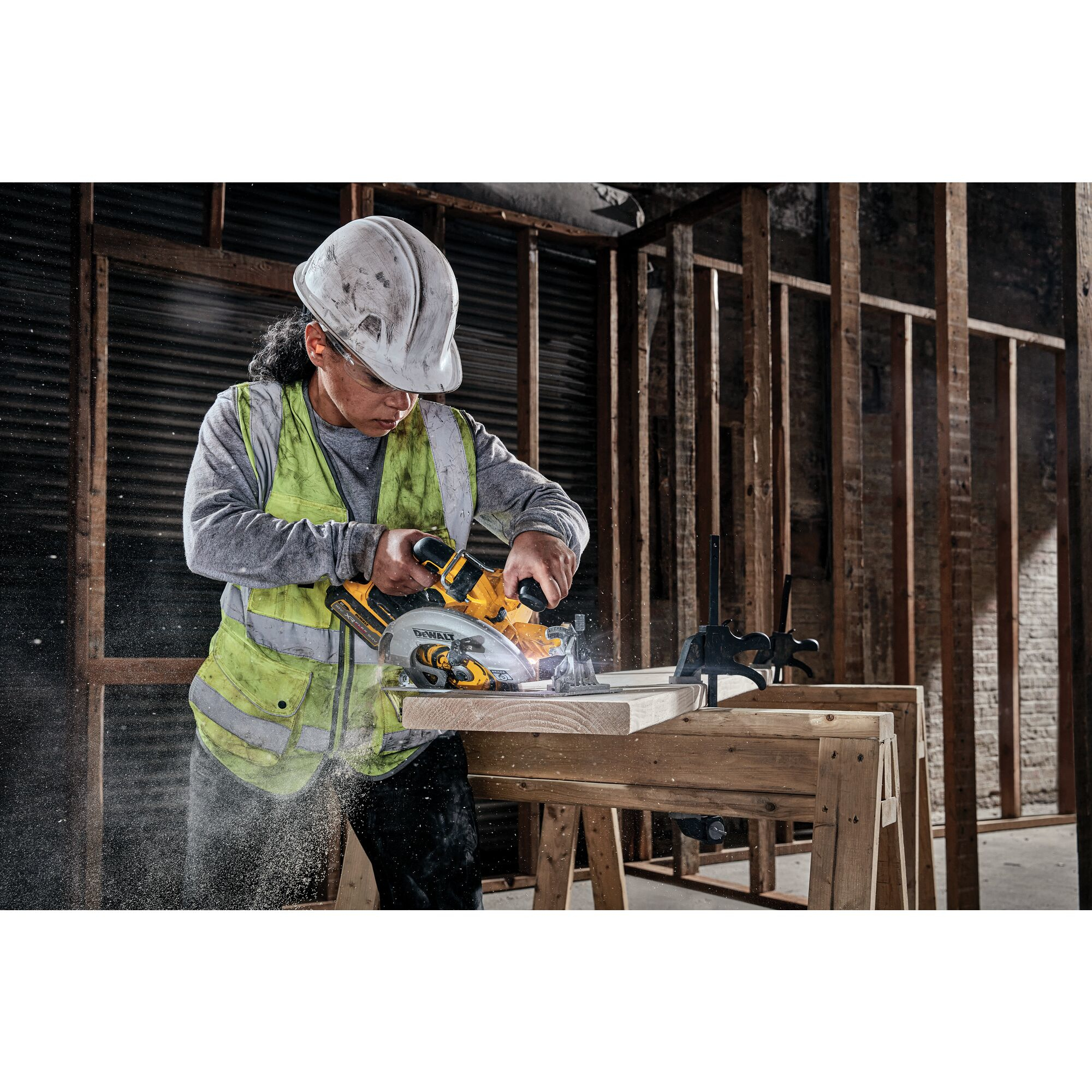 Eine Person auf einer Baustelle schneidet Holz mit einer Kreissäge. Sägemehl ist sichtbar.