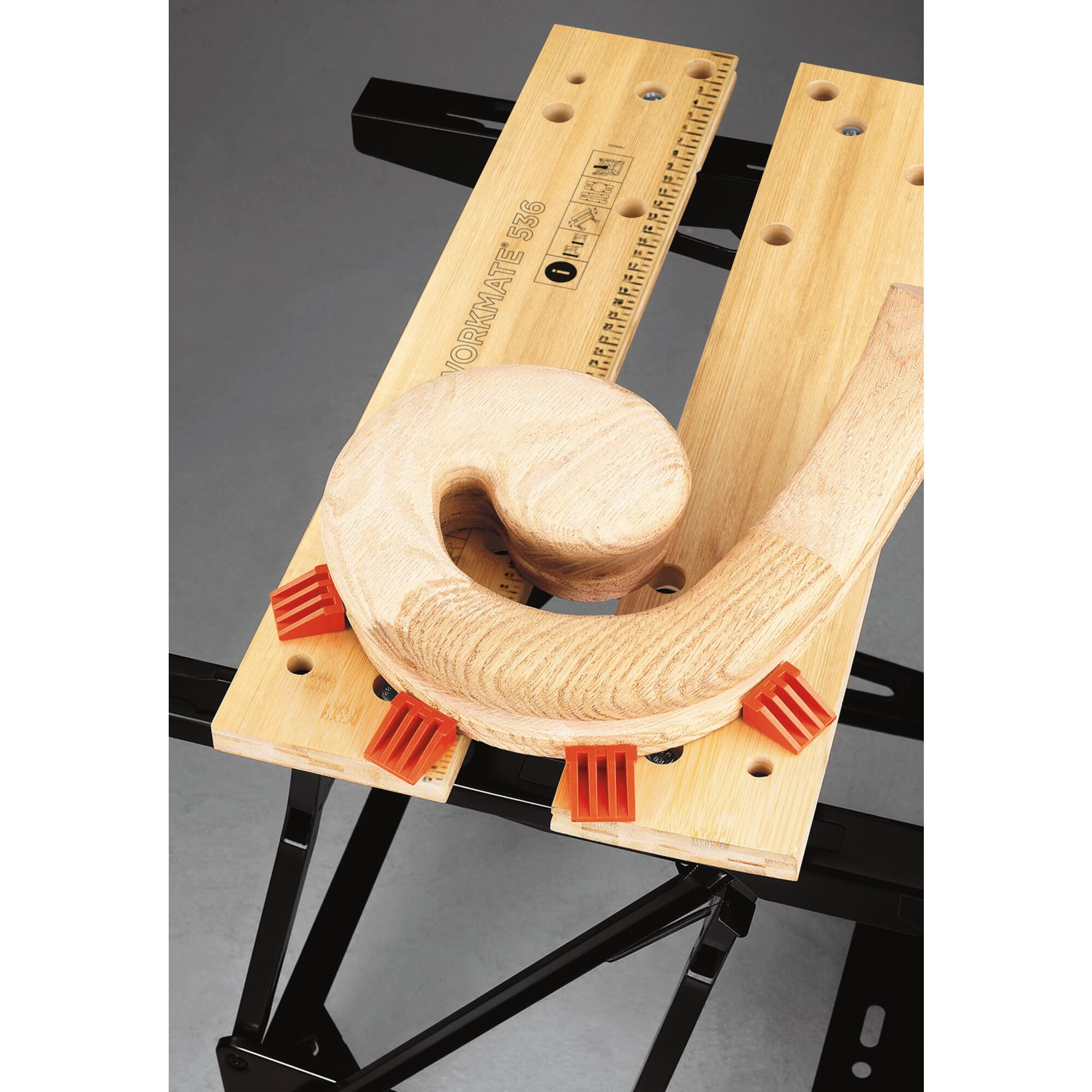 Holzstück auf einem Workmate mit roten Klammern. Das Holzstück ist C-förmig. Im Hintergrund ein Workmate-Tisch.