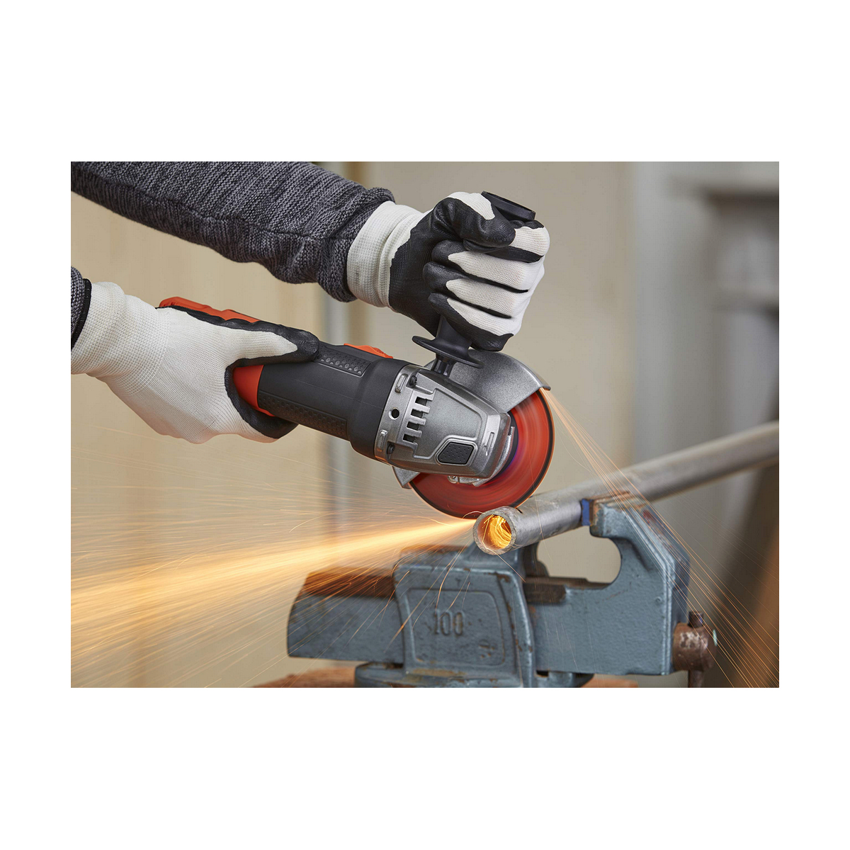 Persoon die een haakse slijper gebruikt op een metalen pijp, vonken vliegen. Ze dragen handschoenen voor de veiligheid.