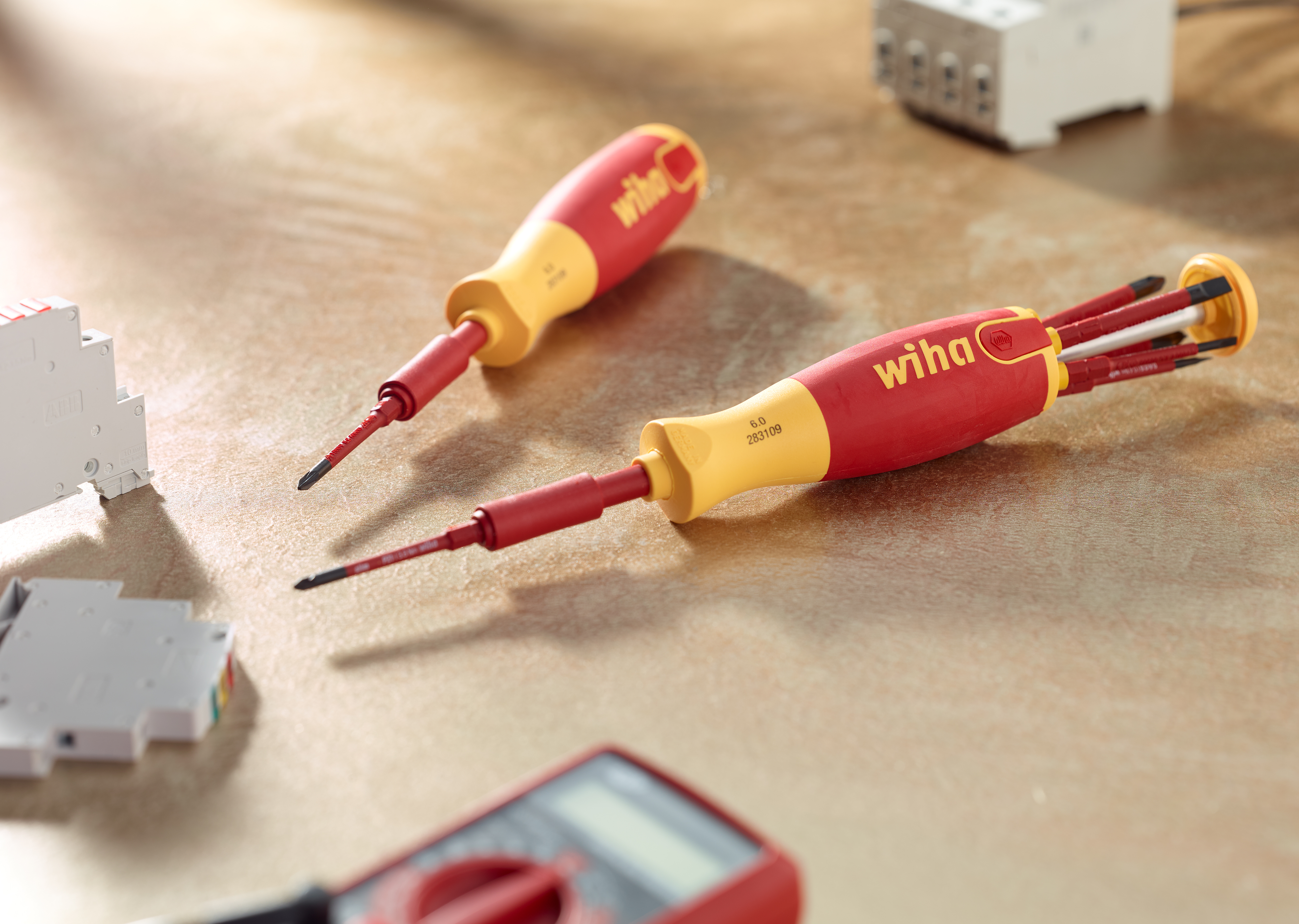 Dos destornilladores Wiha rojos y amarillos, y herramientas sobre madera.