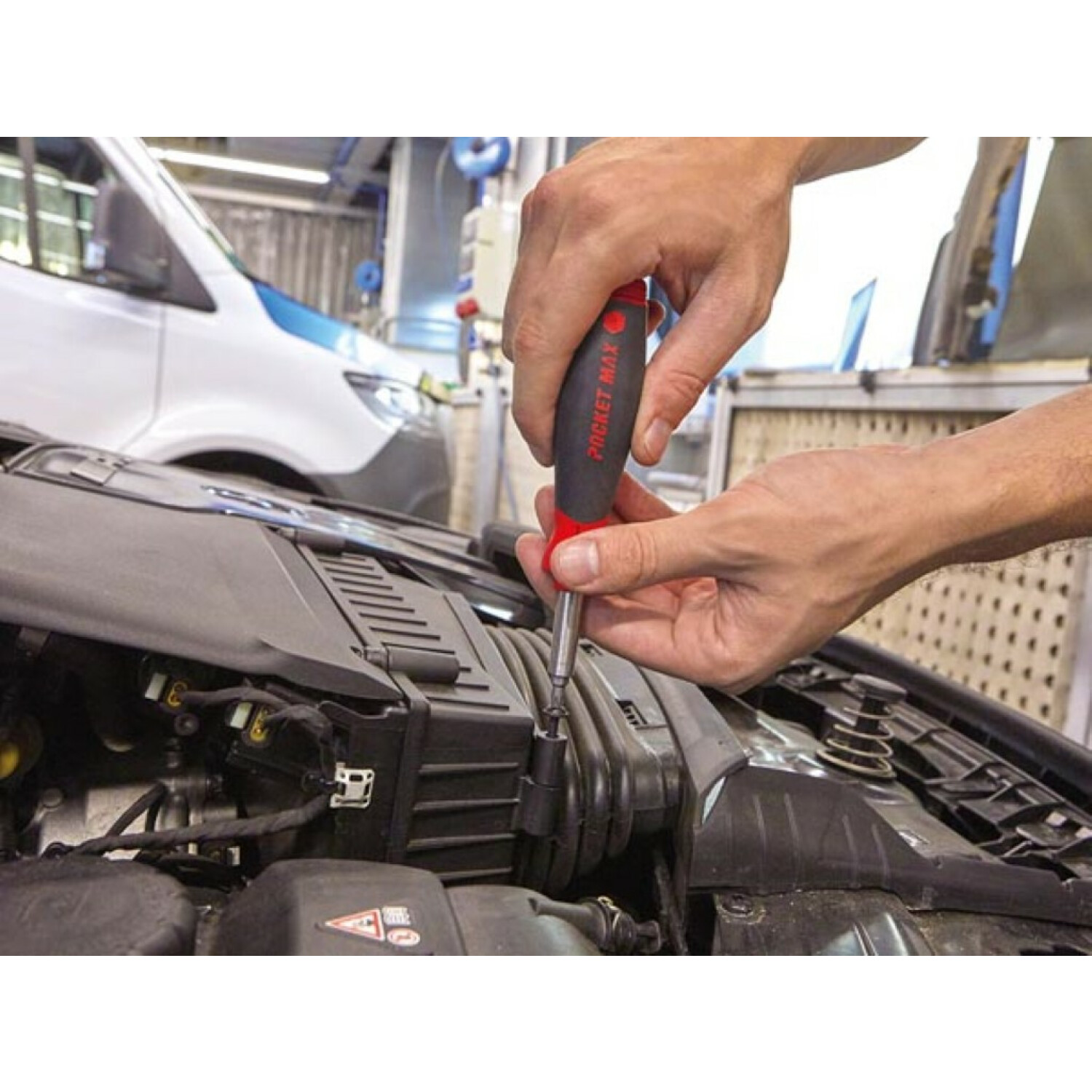 Ręka używa czerwono-czarnego śrubokręta Pocket Max do czarnego elementu silnika.