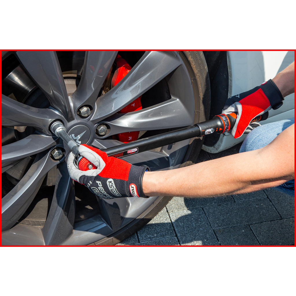 Persona usando una llave dinamométrica en una rueda de coche, con guantes rojos.