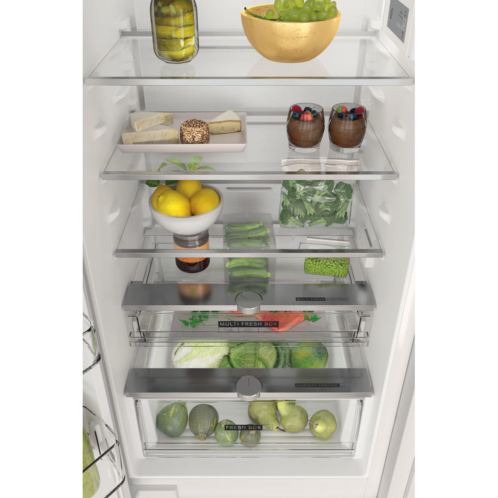 Wnętrze lodówki z różnymi produktami spożywczymi. Półki zawierają słoiki, ser, cytryny i warzywa.