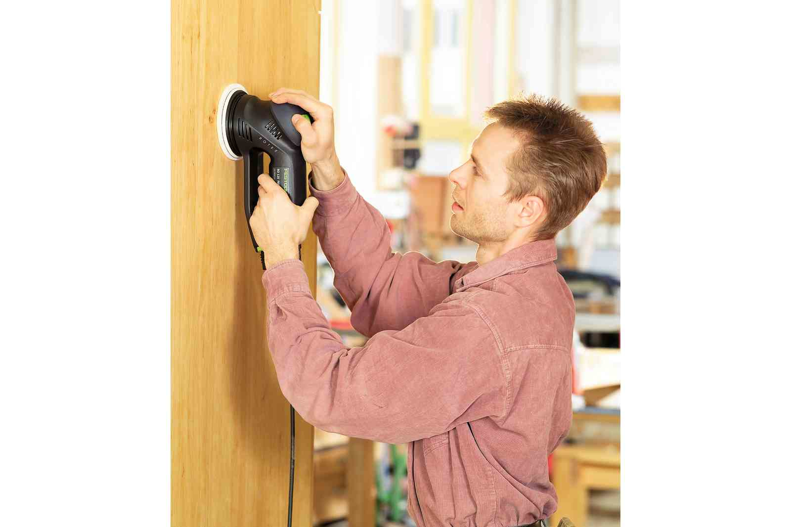 Mężczyzna używa szlifierki elektrycznej na drewnianej ścianie. Szlifierka jest czarno-biała.