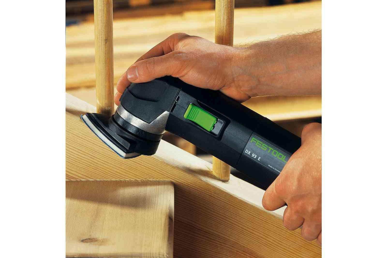 Eine Person benutzt ein schwarz-grünes Elektrowerkzeug auf Holztreppen.