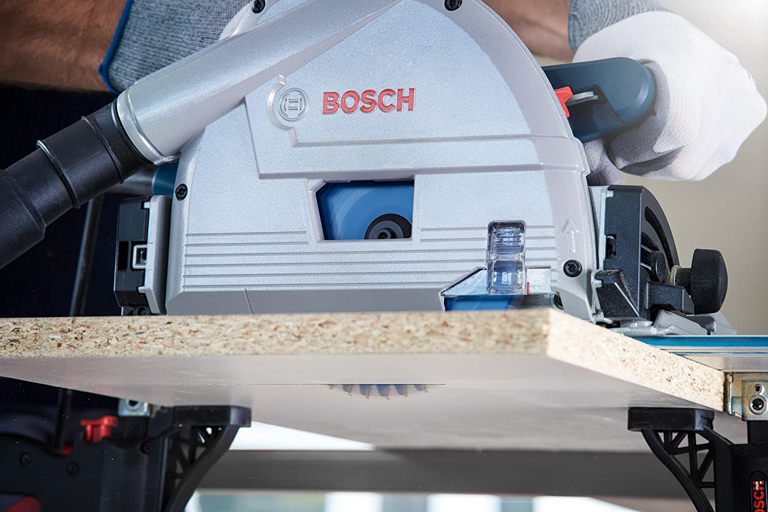 Una persona usa una sega circolare per tagliare un pezzo di legno. La sega ha il logo Bosch.