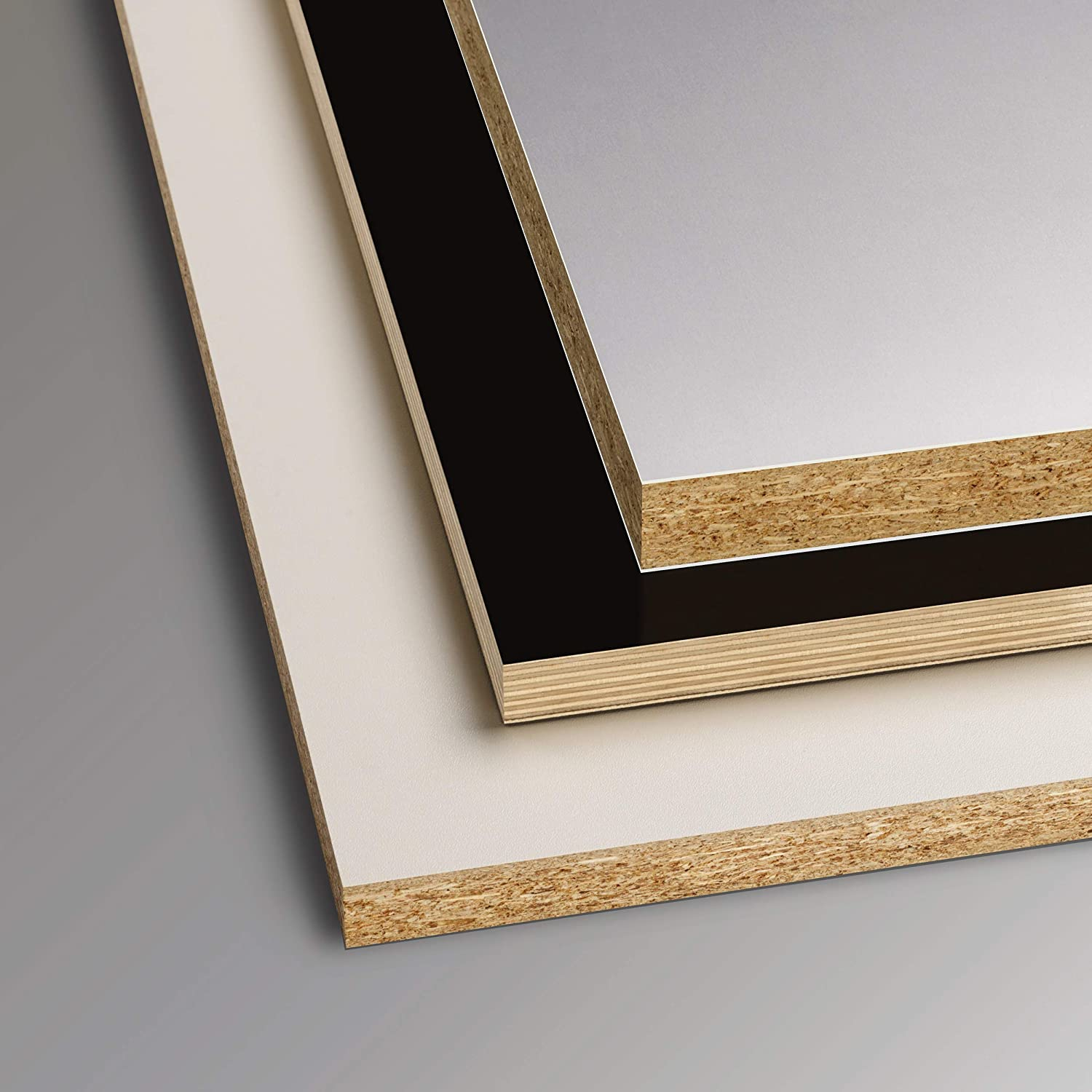 Tre pannelli di legno a strati con superfici bianche, nere e grigie e bordi con venature del legno.