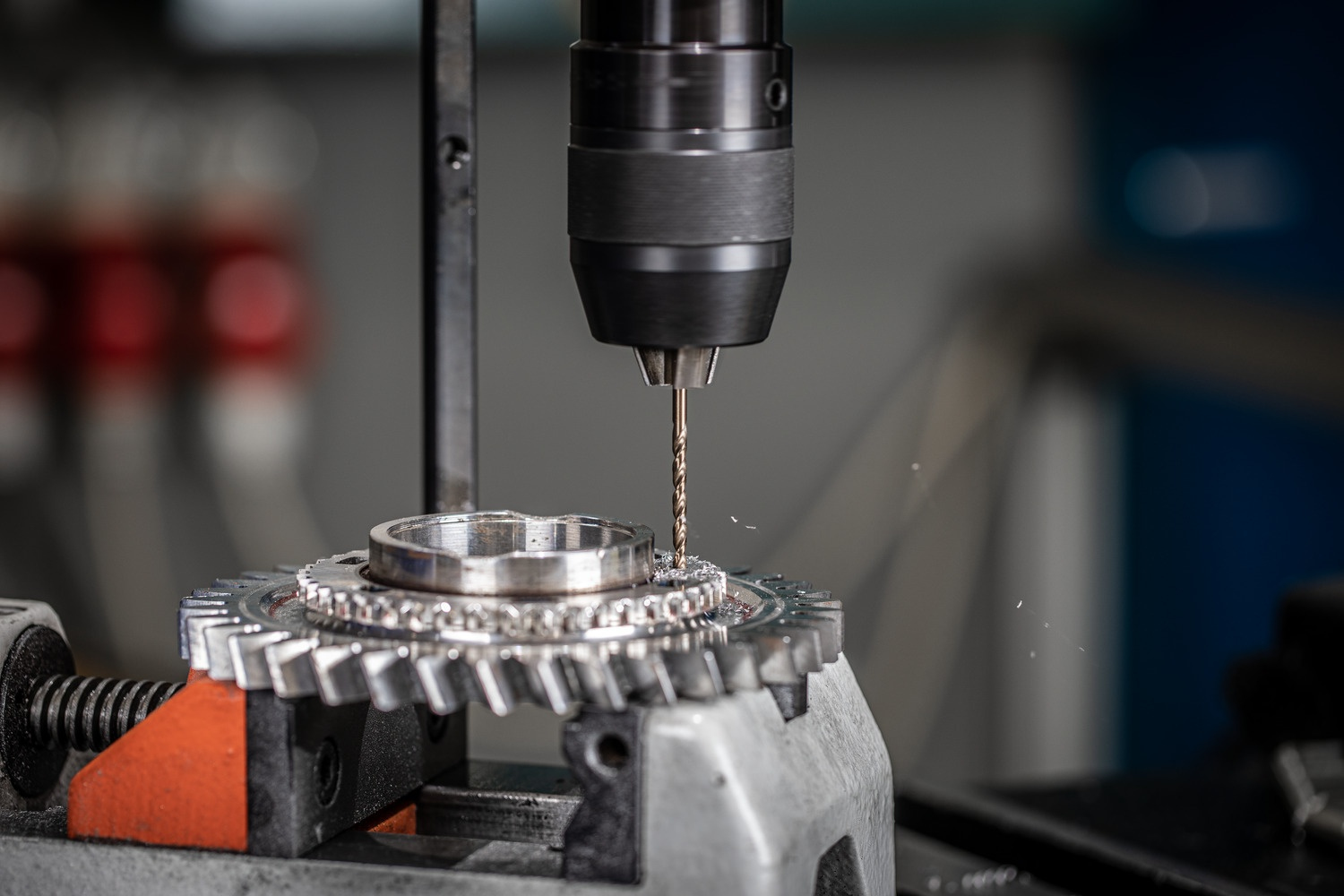 Eine Bohrmaschine bohrt in ein Metallzahnrad. Nahaufnahme mit Fokus auf Bohrer und Zahnrad.