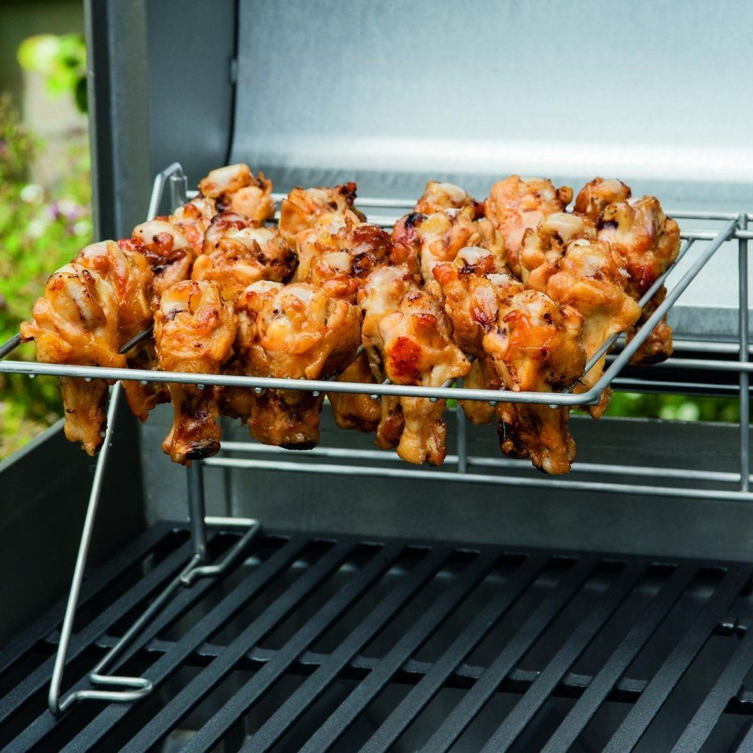 Primer plano de alitas de pollo a la parrilla en una rejilla metálica, listas para servir. La rejilla está en una parrilla.