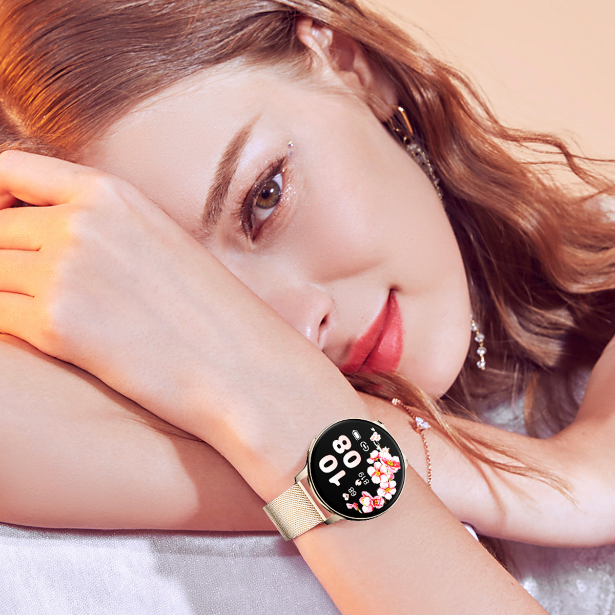 Eine Frau trägt eine goldene Smartwatch am Handgelenk. Das Zifferblatt zeigt Blumen.
