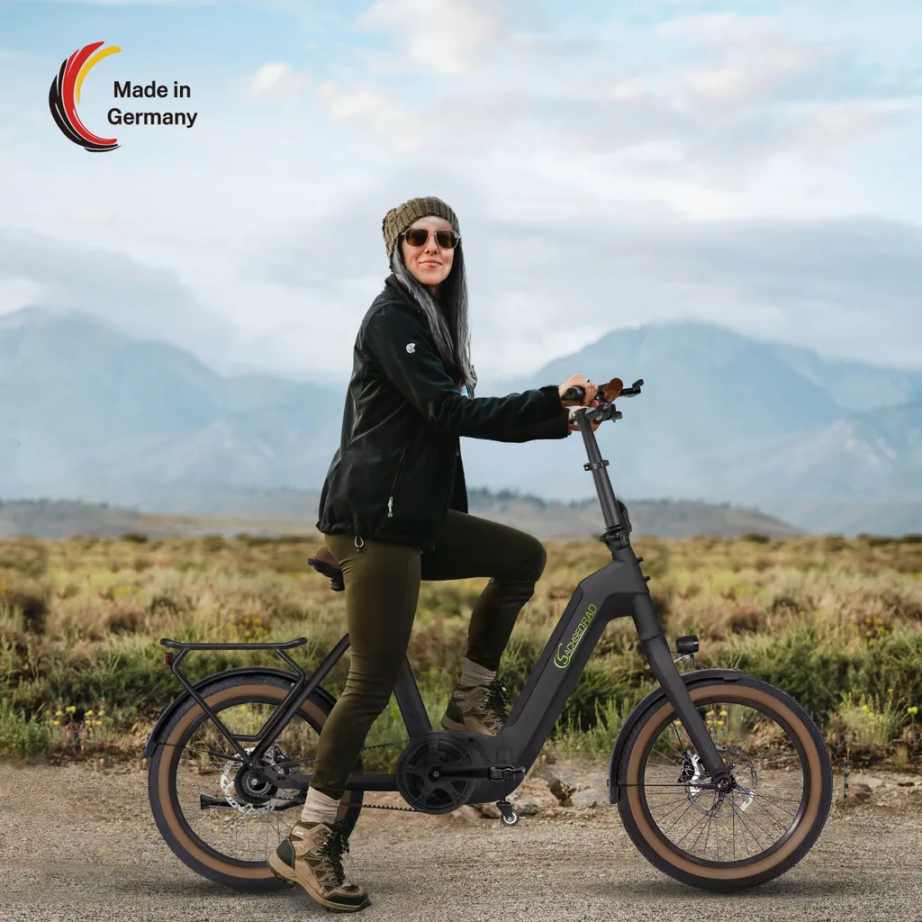 Frau fährt auf einem schwarzen Elektrofahrrad in einer malerischen Landschaft. Berge im Hintergrund.