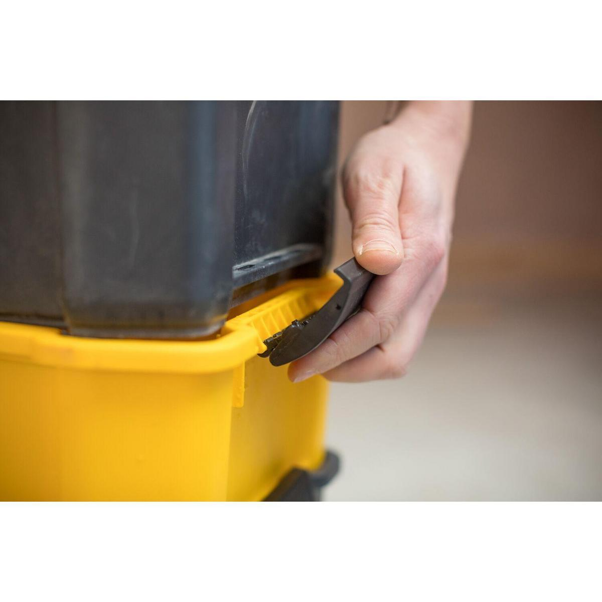 Ręka łączy warstwy skrzynki narzędziowej, blokując żółto-czarną skrzynkę.