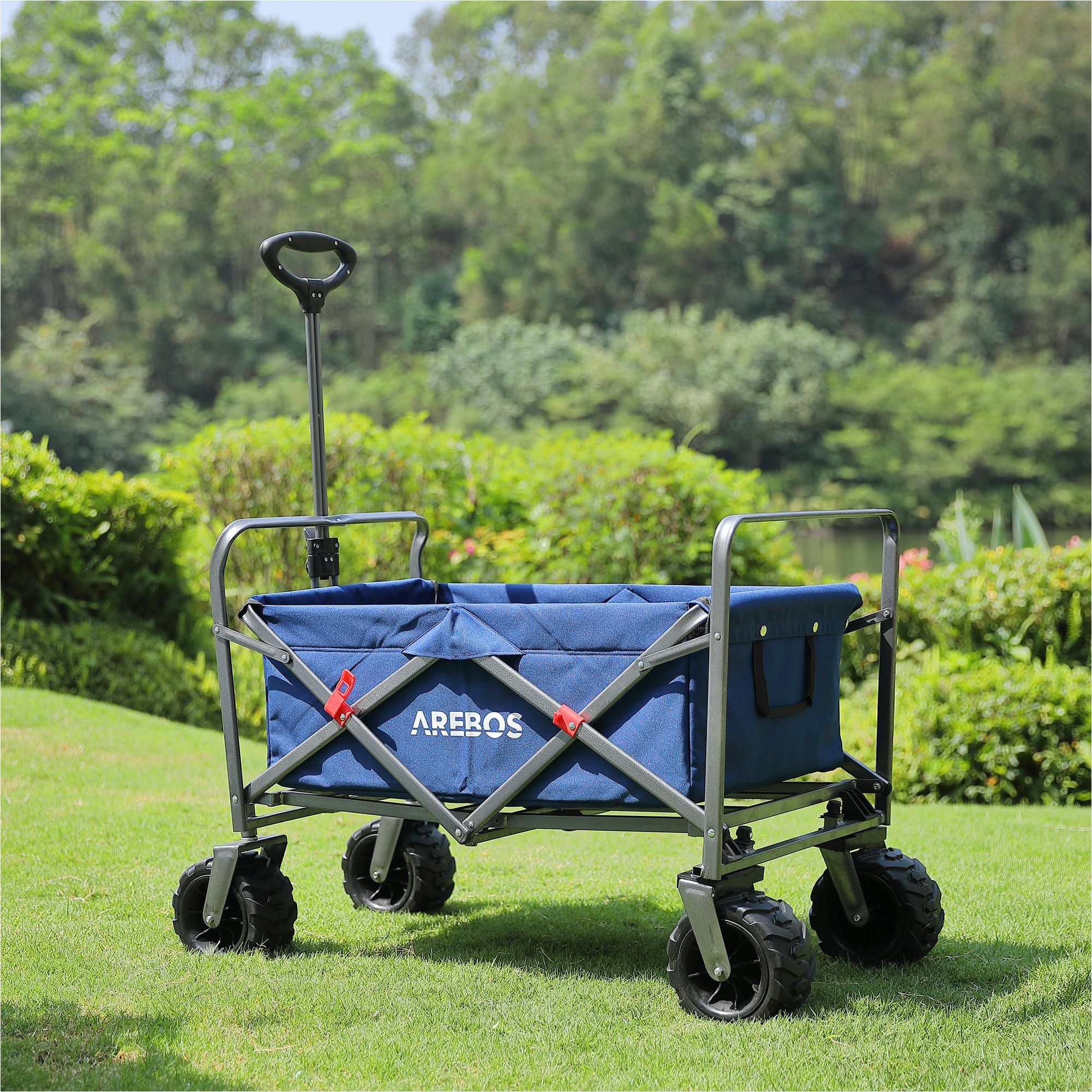 Blauer Klappwagen auf Gras. Der Wagen befindet sich in einem Garten mit grünem Hintergrund.