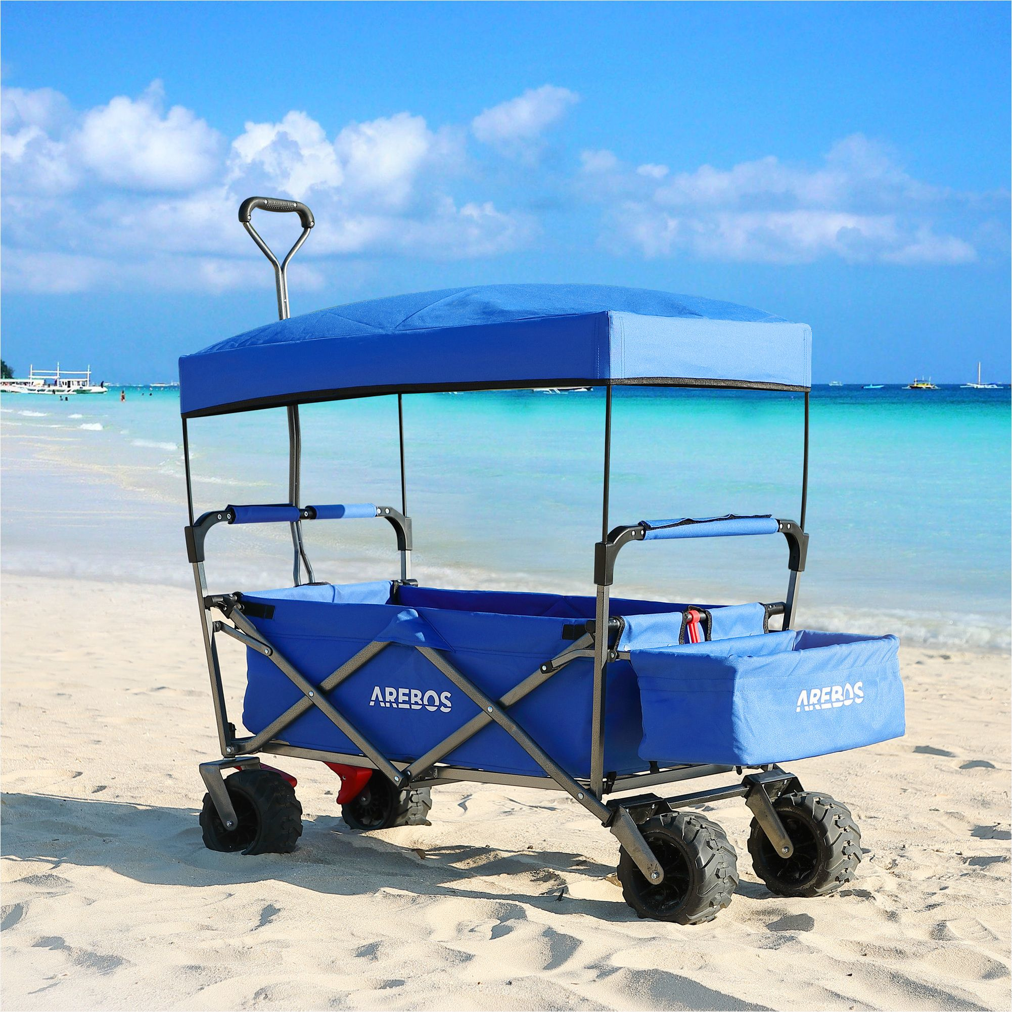 Blauer Strandwagen mit Sonnensegel auf dem Sand.