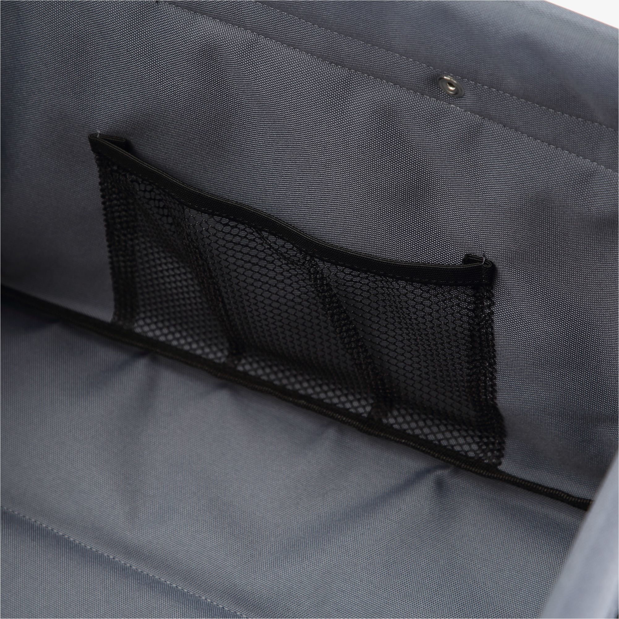 Nahaufnahme des grauen Innenraums einer Tasche. Eine schwarze Netztasche ist auf den grauen Stoff genäht.