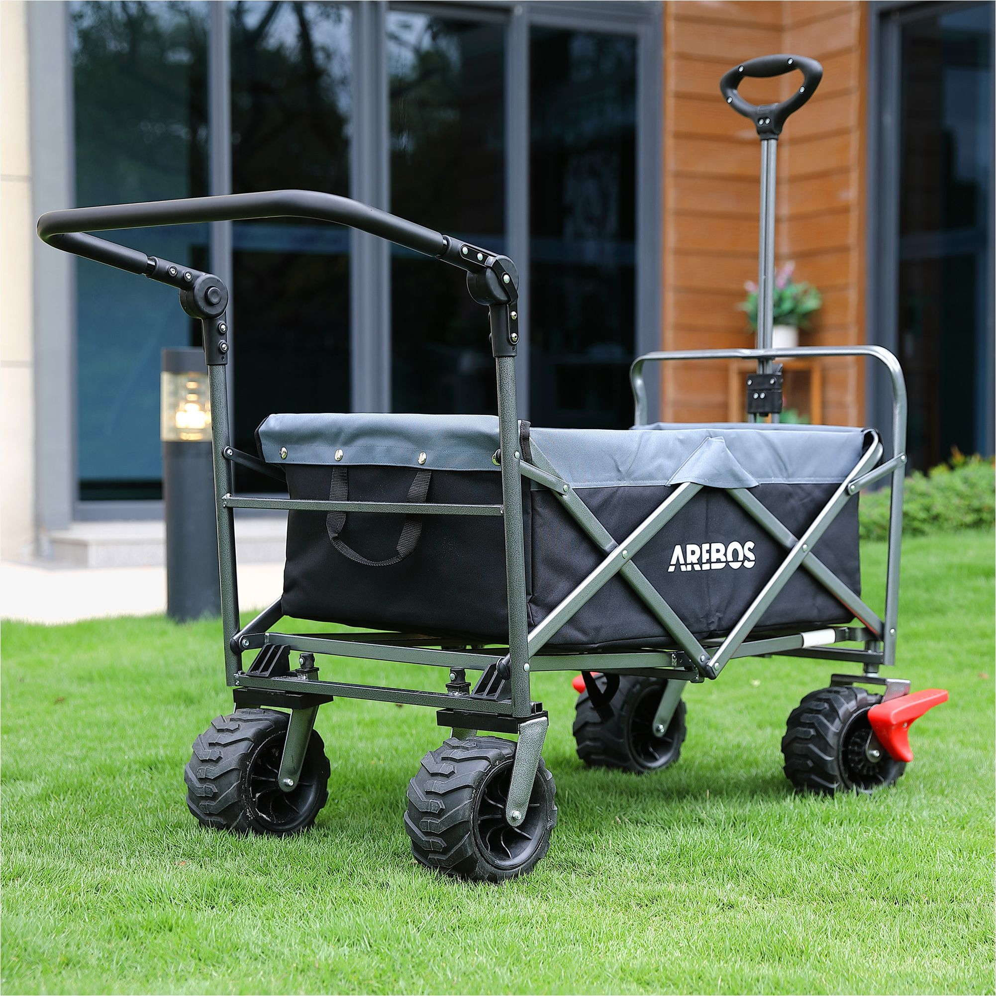 Ein schwarzer Transportwagen auf Gras. Er hat große Räder und ist mit Gegenständen beladen.