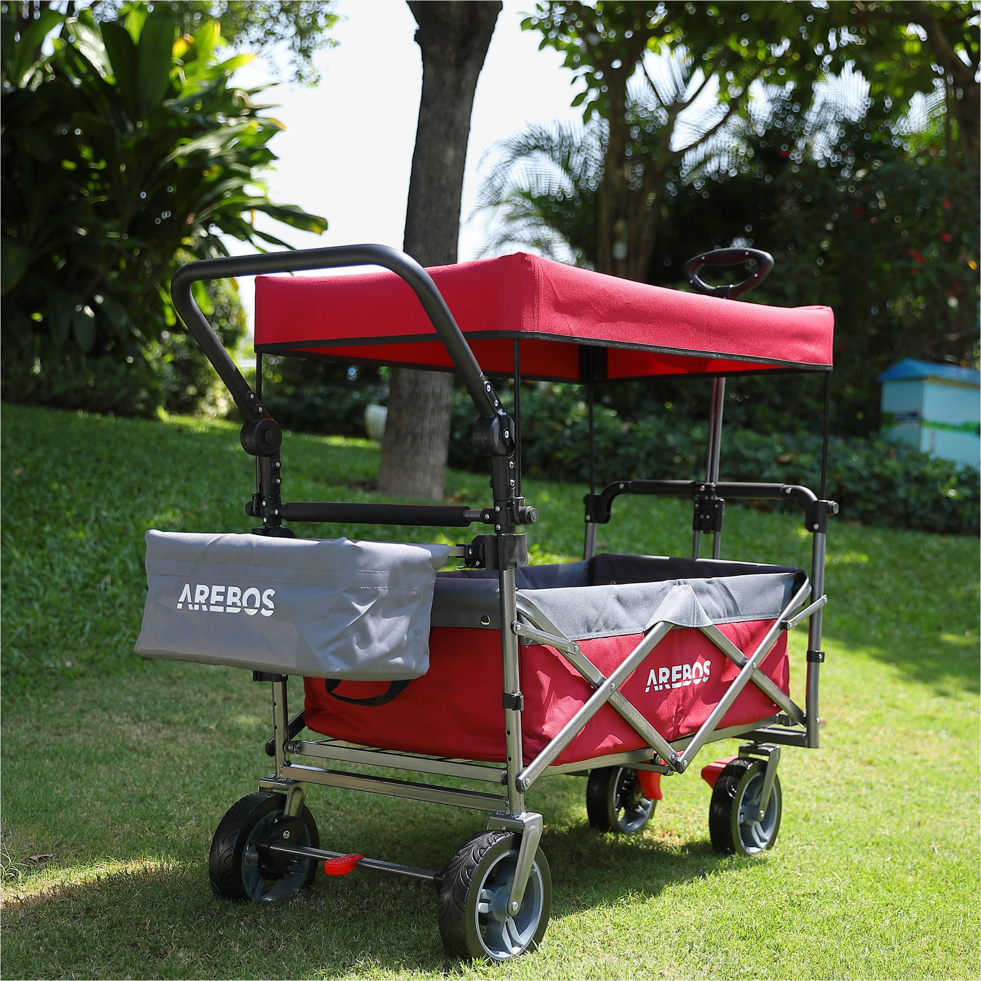 Ein roter und grauer Wagen mit Verdeck steht auf grünem Gras.