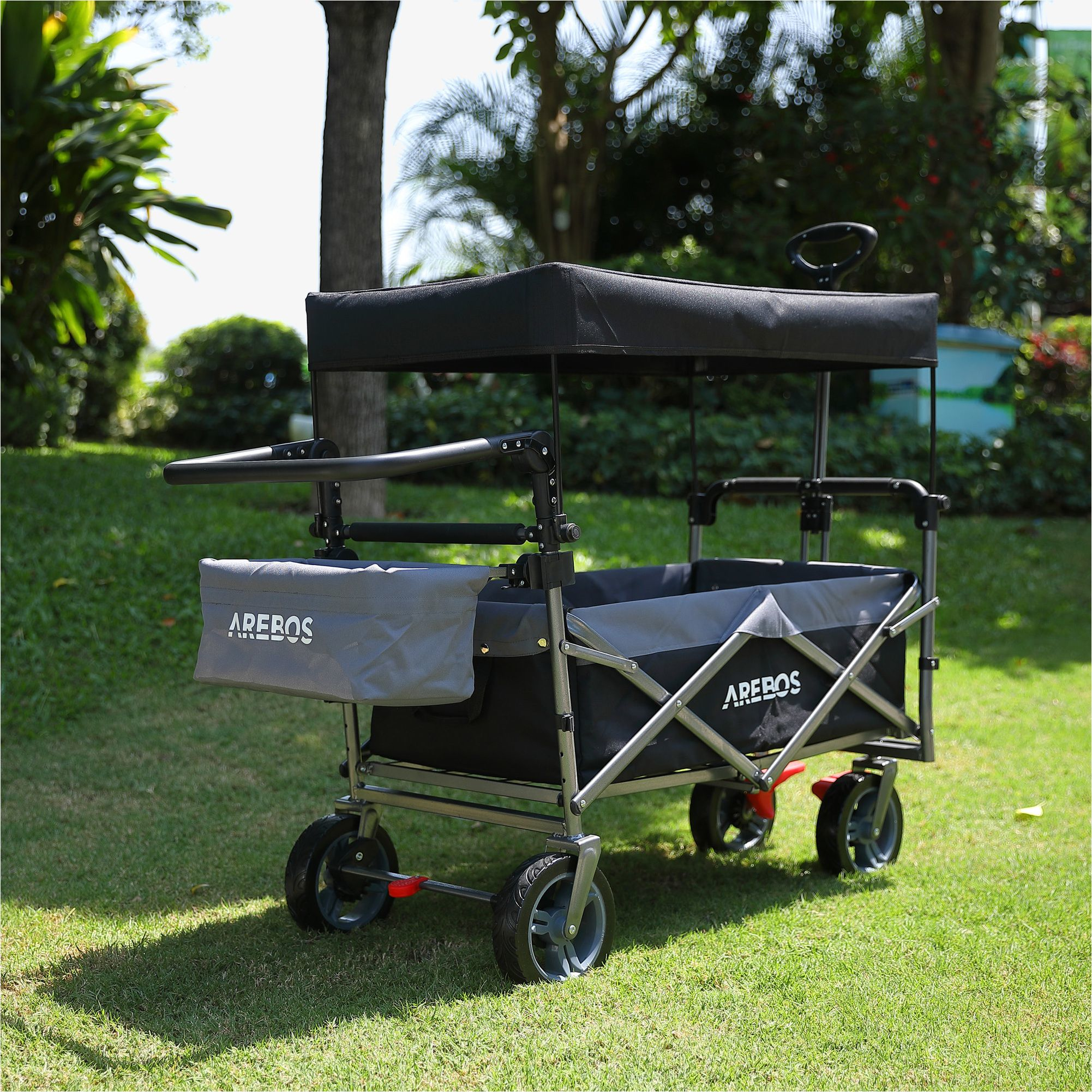 Ein faltbarer Wagen steht auf Gras. Er hat ein Verdeck, eine Aufbewahrungstasche und ein grau-schwarzes Design.