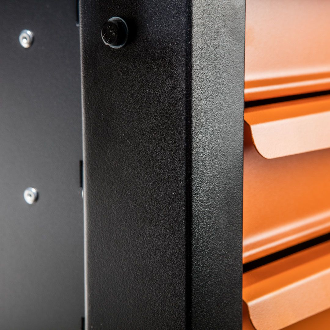 Nahaufnahme eines schwarzen Metallschranks mit orangefarbener Schublade. Befestigungselemente sind sichtbar.