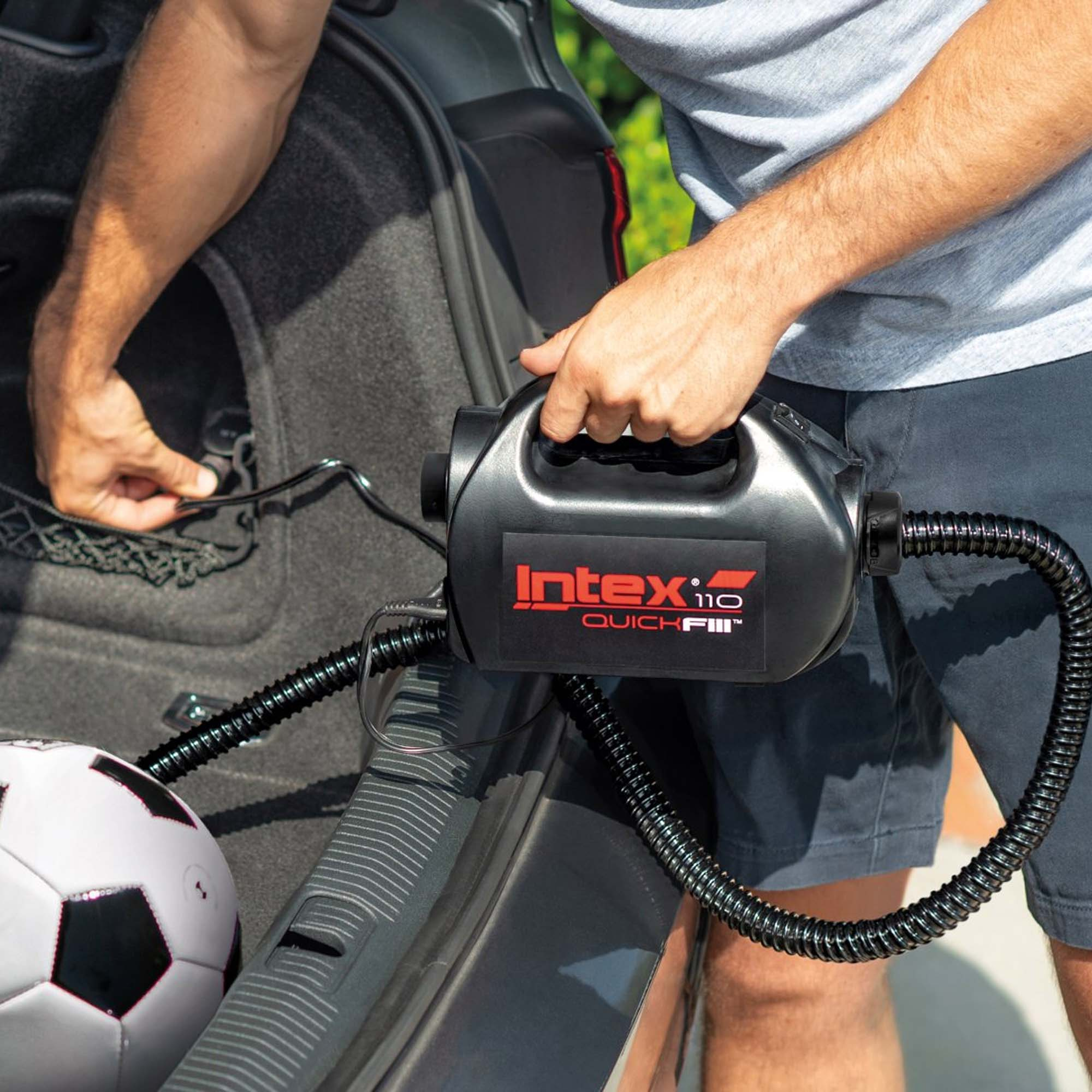 Osoba trzymająca czarną pompę Intex Quick Fill 110 obok samochodu, widoczna piłka nożna.