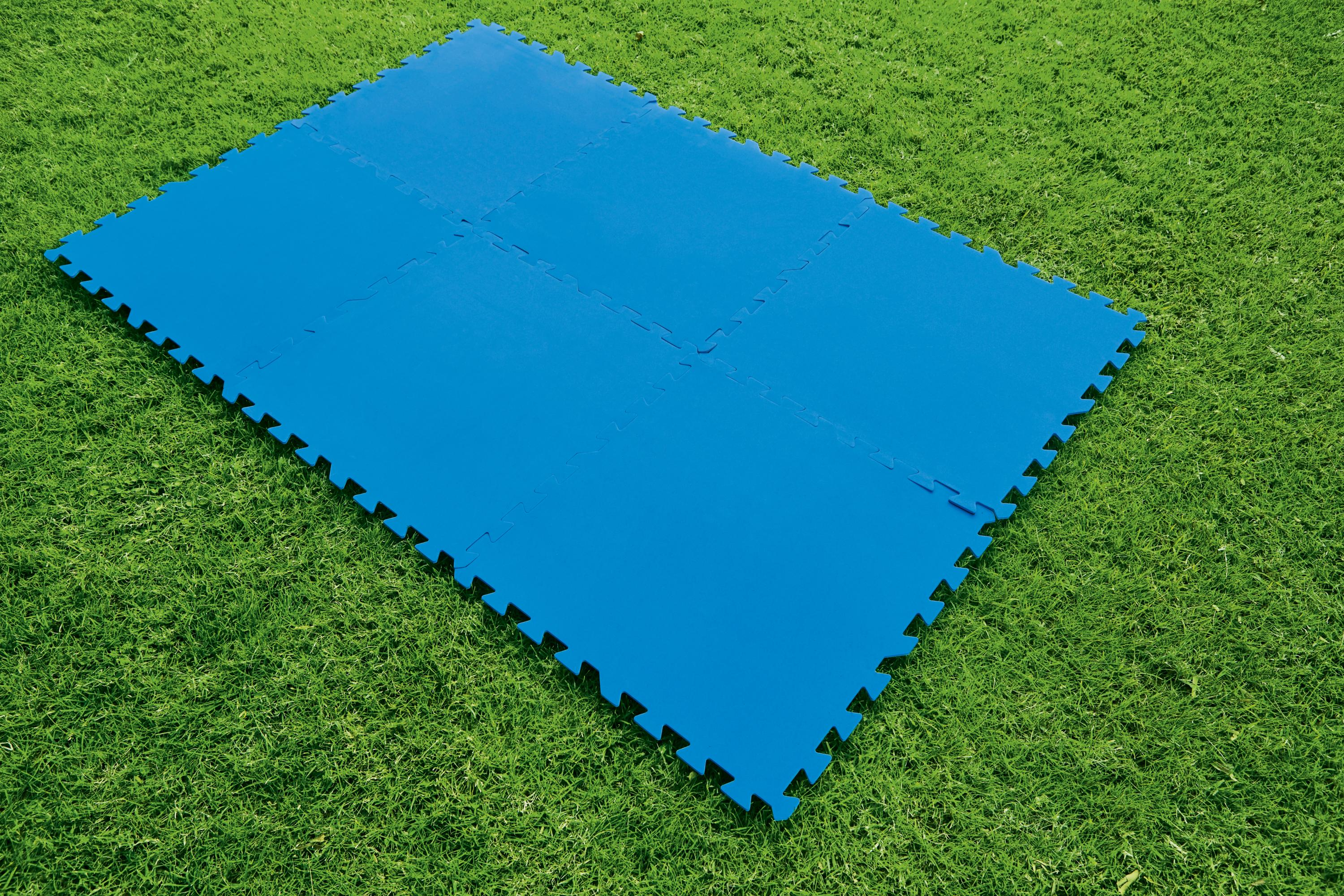 Esteras protectoras de piso azules dispuestas sobre un área de césped verde.