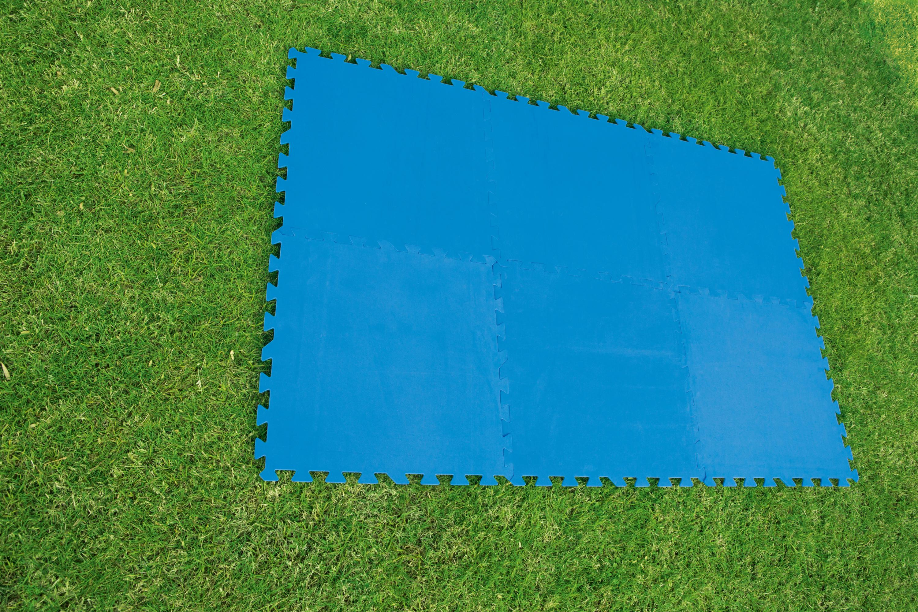 Esteras protectoras de piso azules dispuestas sobre un área de césped verde.