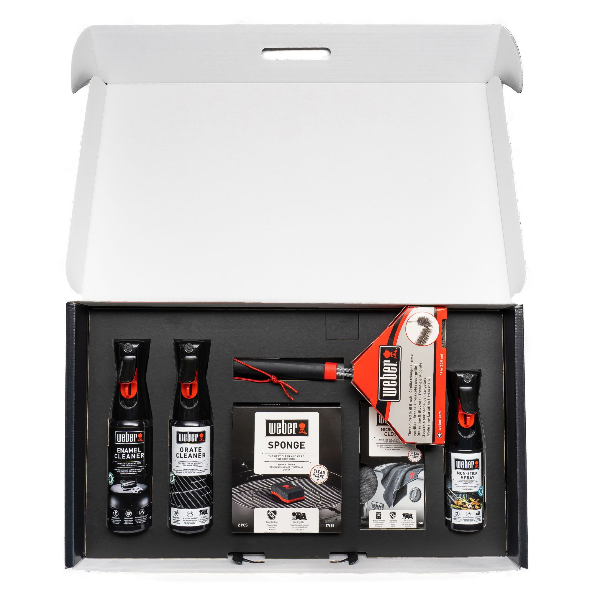 Pudełko z akcesoriami do czyszczenia grilla. Pudełko jest otwarte, pokazując różne butelki, gąbkę i szczotkę.