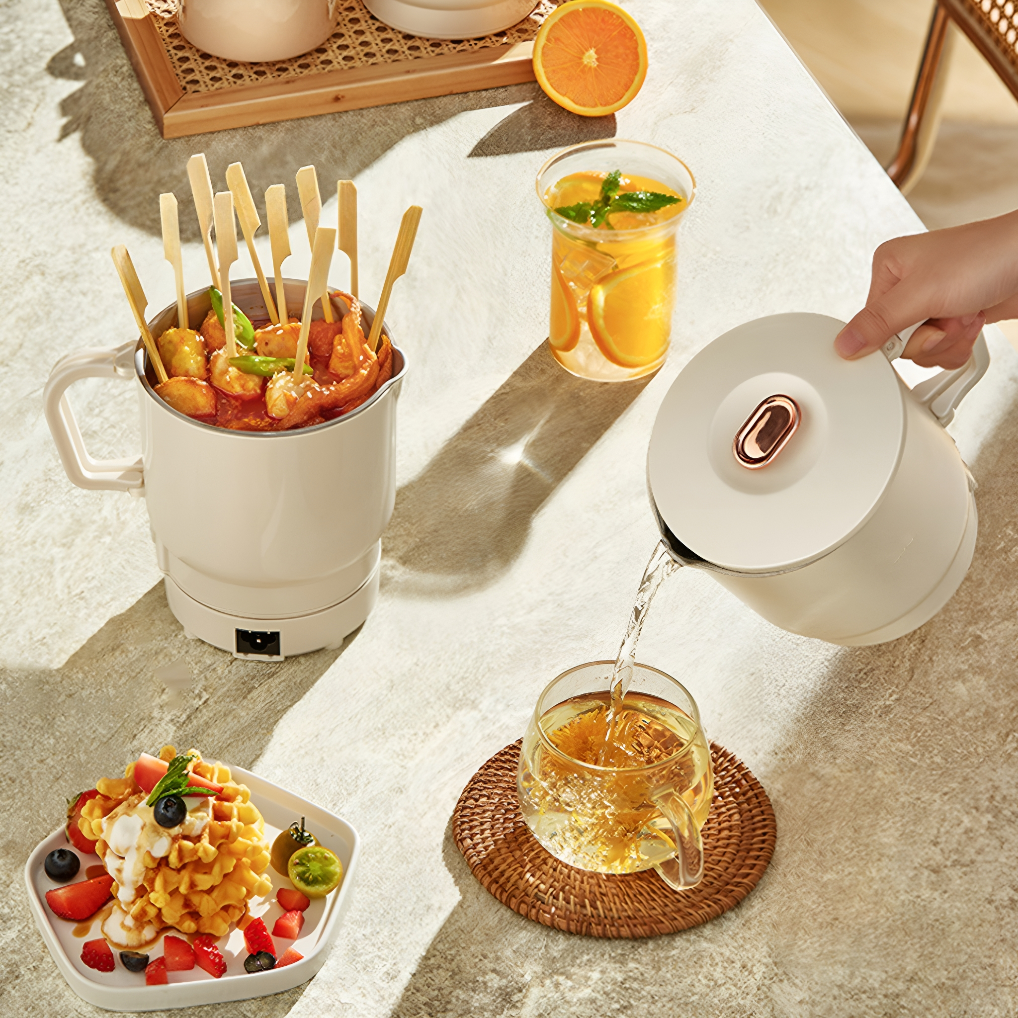 Tisch mit Mini-Kochtopf, Essensspießen, Saft und Waffelplatte. Jemand gießt Wasser ein.