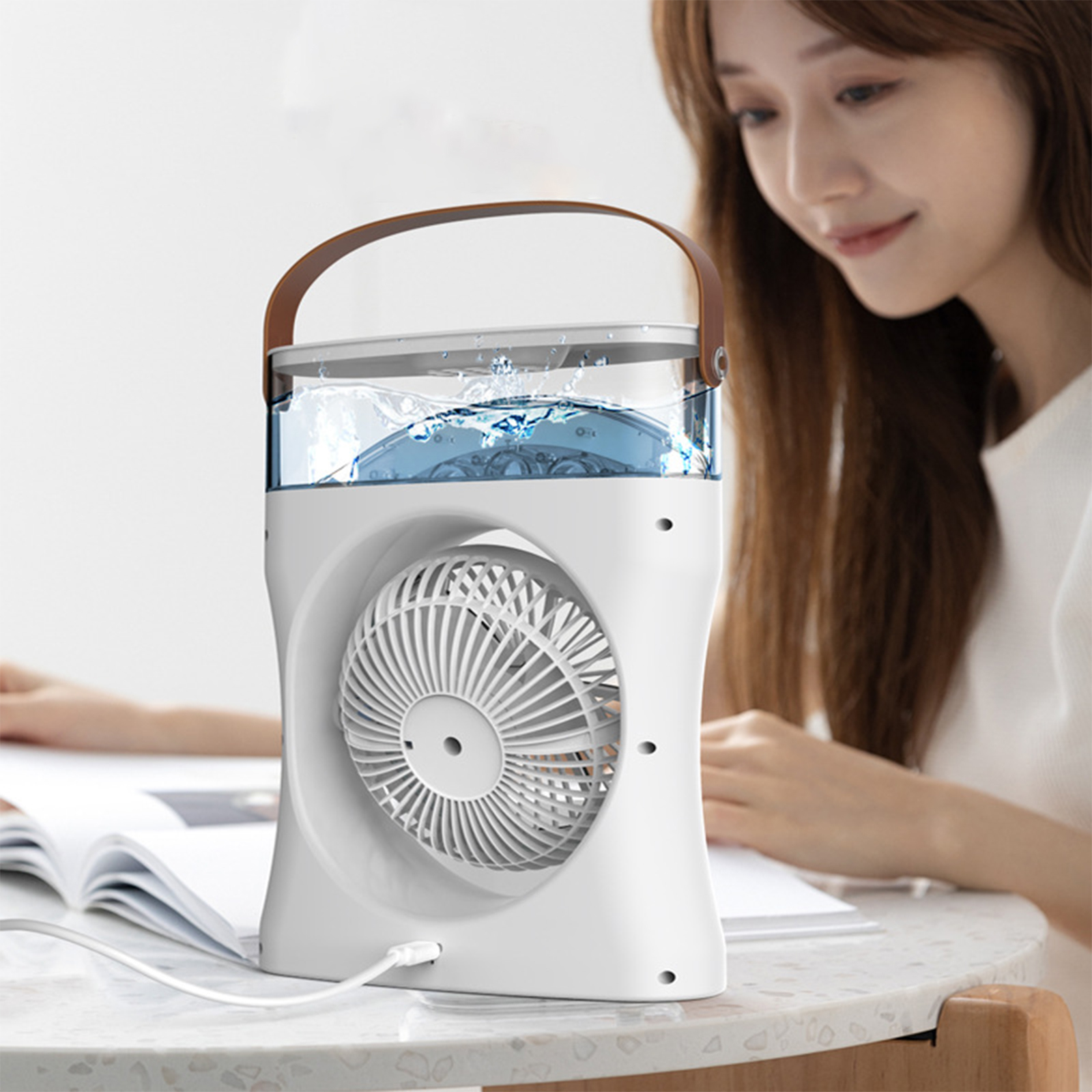Ein weißer tragbarer Ventilator mit Wasser. Eine Frau sitzt daneben und liest ein Buch.